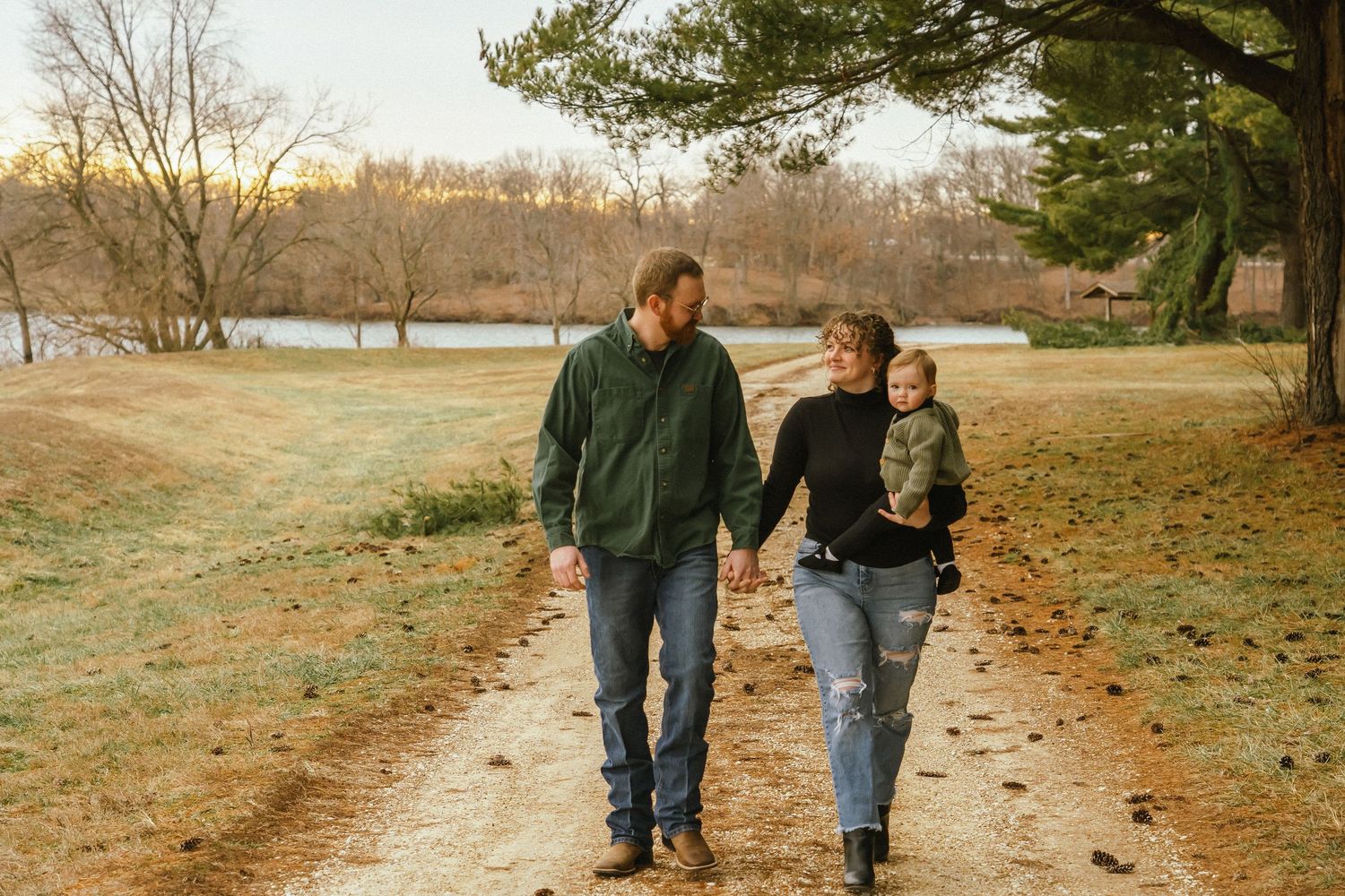 Couple walking together on a leaf-covered path through an autumn park during golden hour.