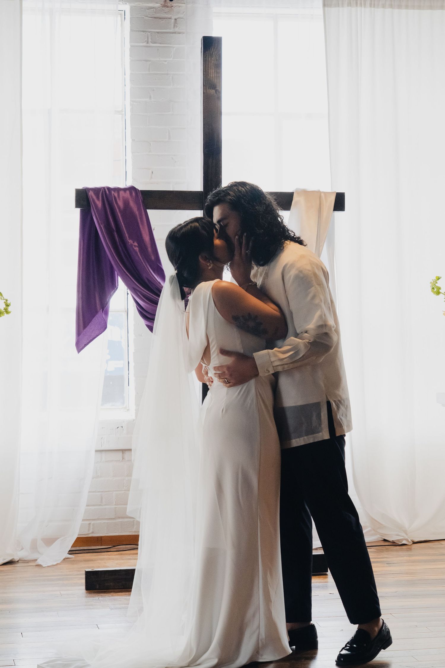 A tender first look moment between a couple in a bright white room with flowing curtains.