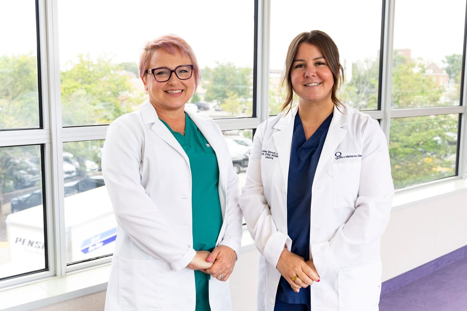 Medical professionals in white coats standing together in a bright office hallway.