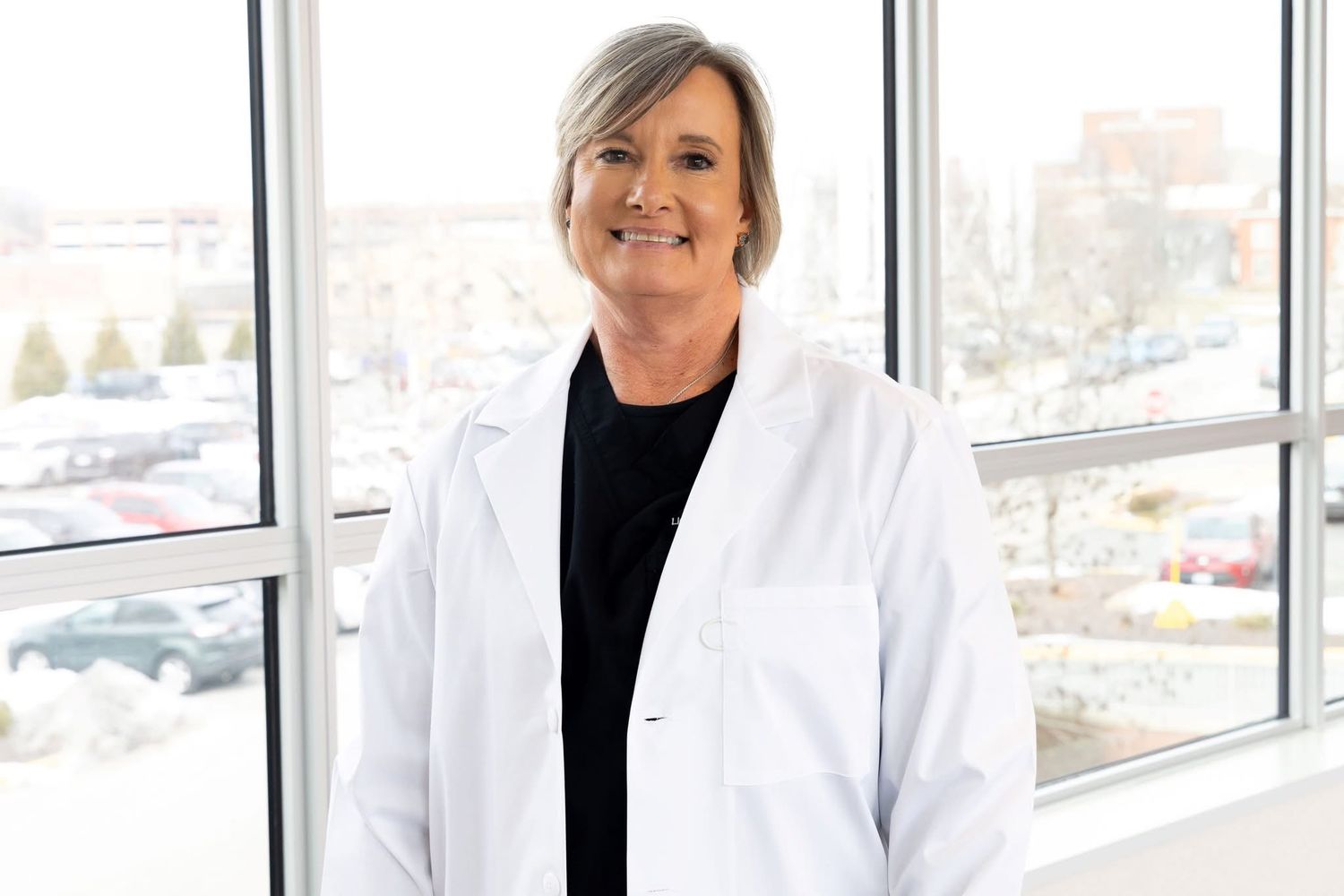 Healthcare professional in white coat standing in modern medical office setting.