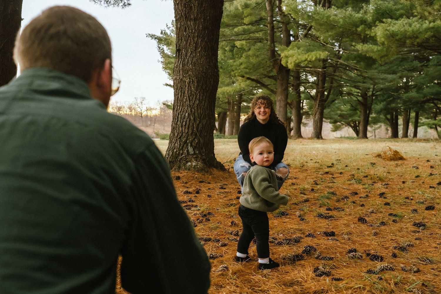 Family enjoying quality time together in a park with autumn leaves scattered on the ground.
