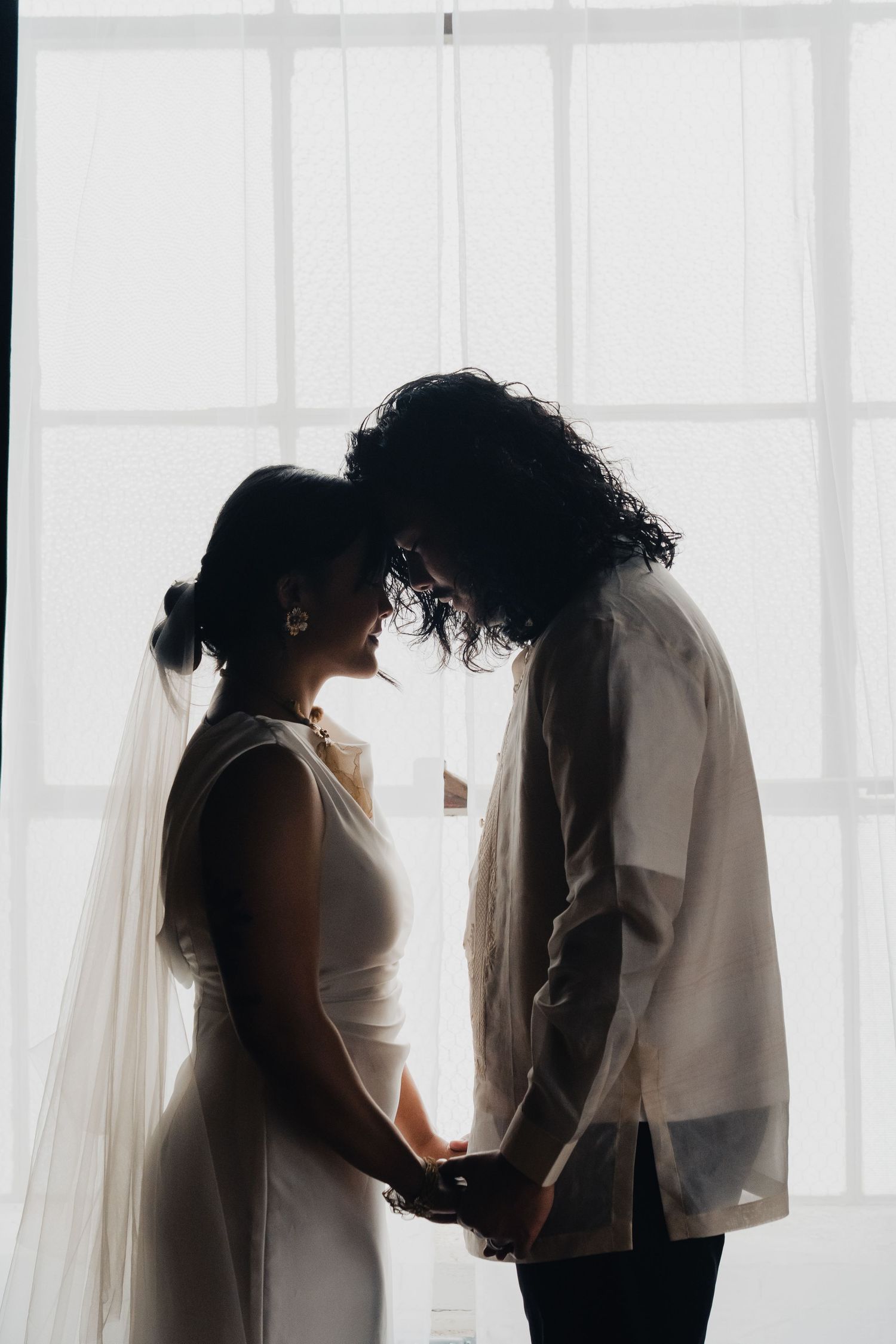 A series of silhouetted couples sharing intimate moments against bright white windows in a wedding setting.