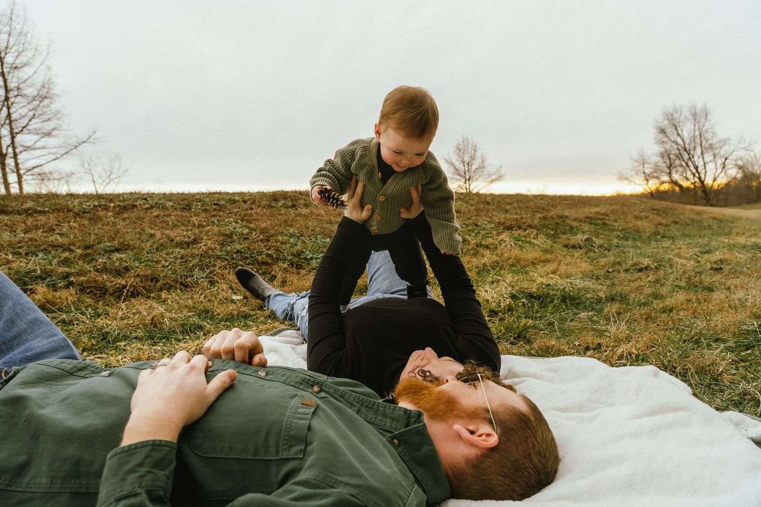 Family having fun together laying on a blanket outdoors during golden hour in autumn.