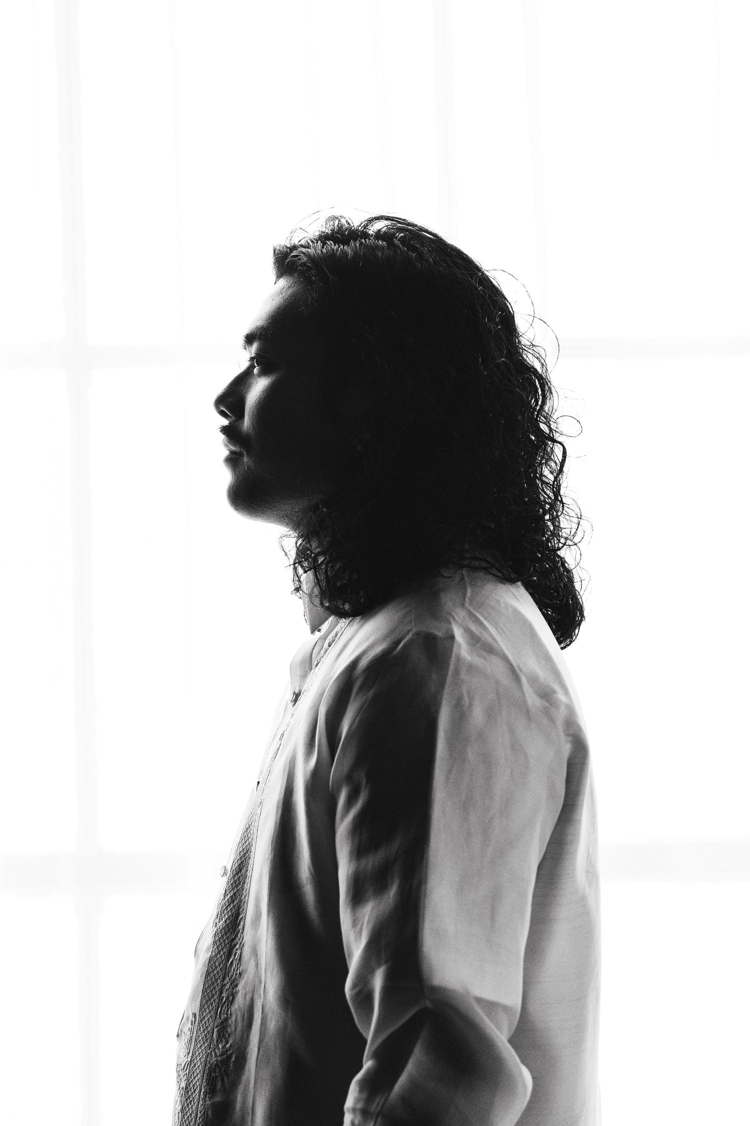 Artistic black and white profile silhouette showing three poses of a person with curly hair looking upward.