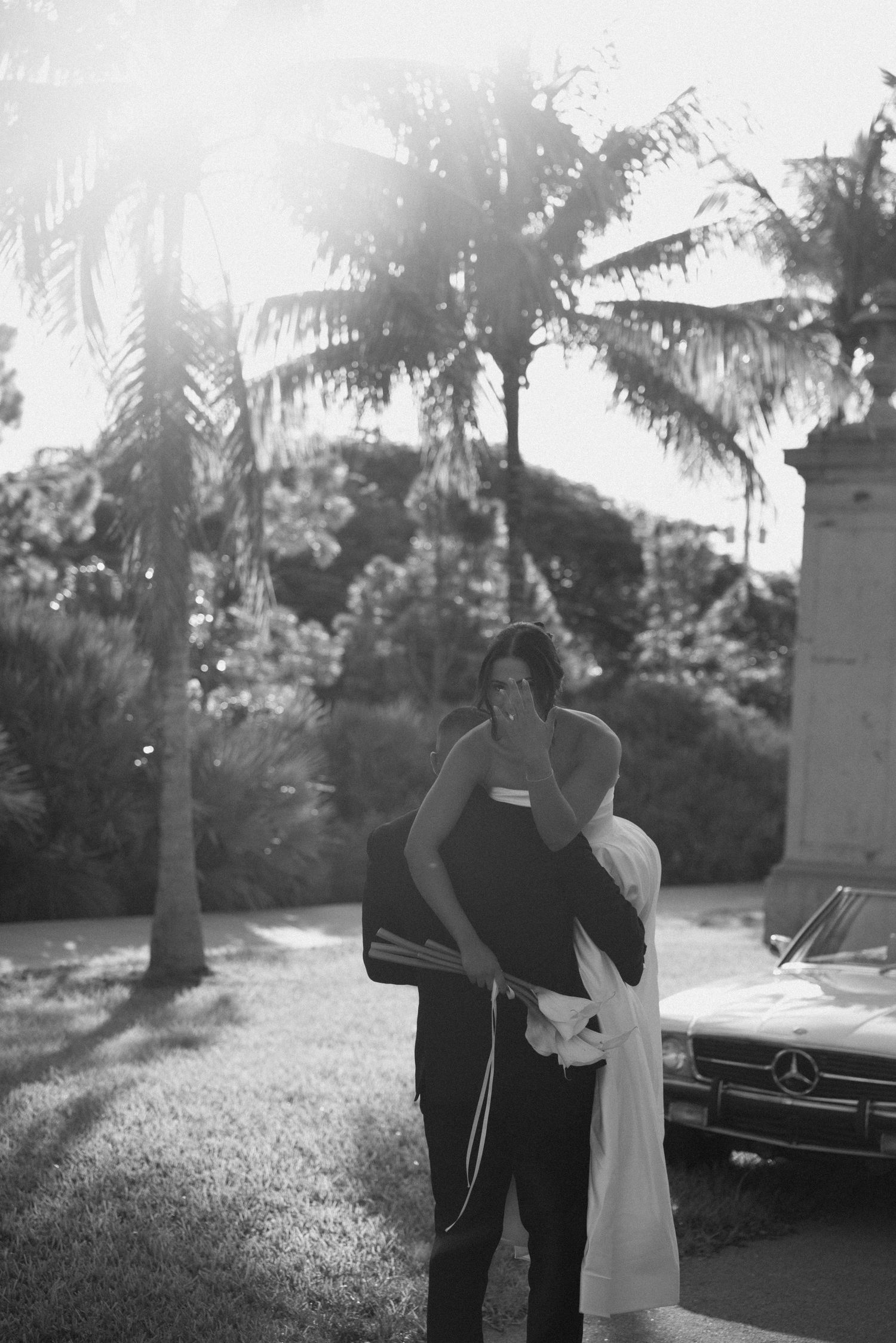 A black and white photo sequence shows two people standing near a classic car in a palm tree-lined setting.