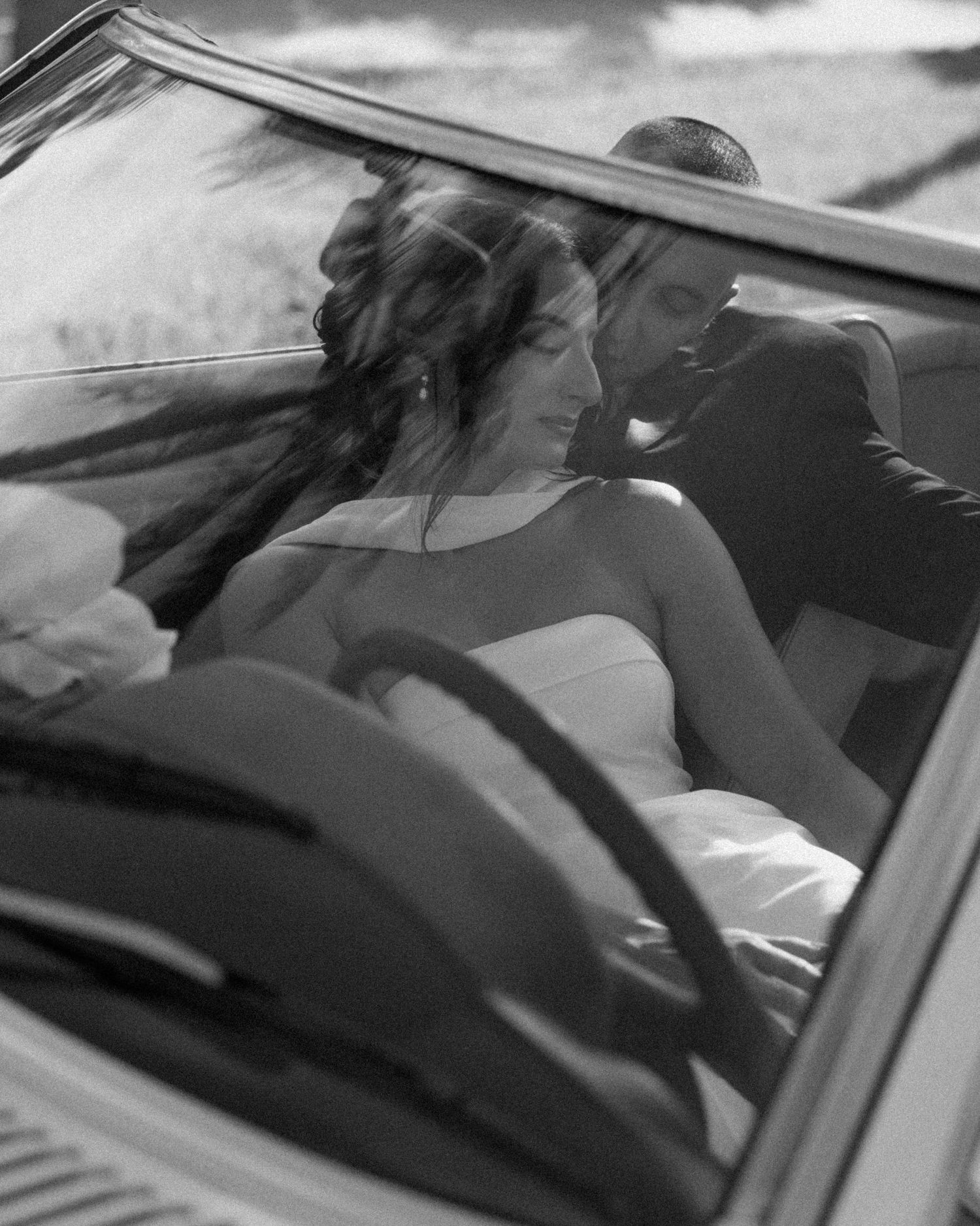 A person in a car leans over while driving in a black and white sequence of motion shots.