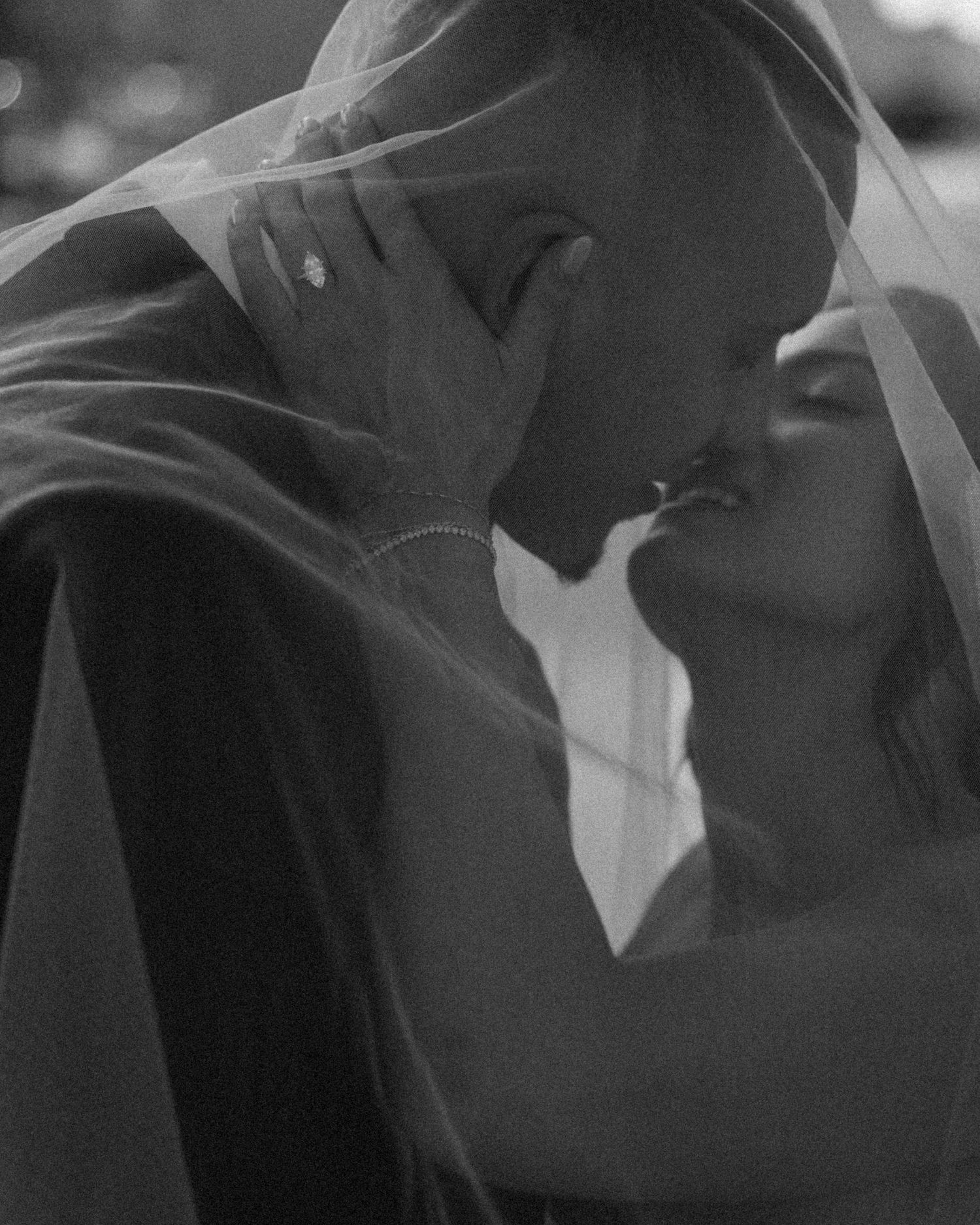 A romantic black and white photo of a couple sharing an intimate moment under a delicate veil.