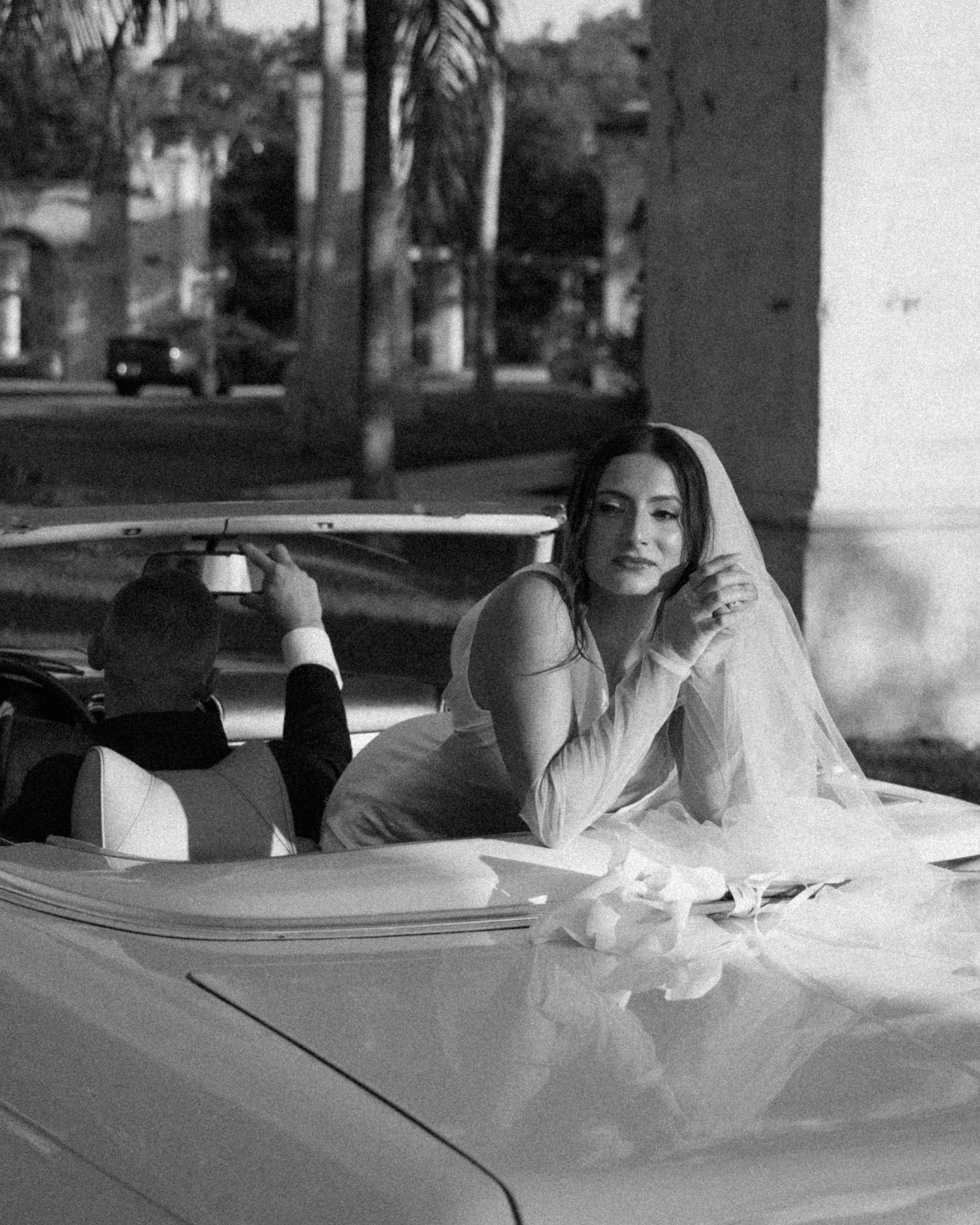 A series of black and white photos showing someone lounging in a classic convertible car.
