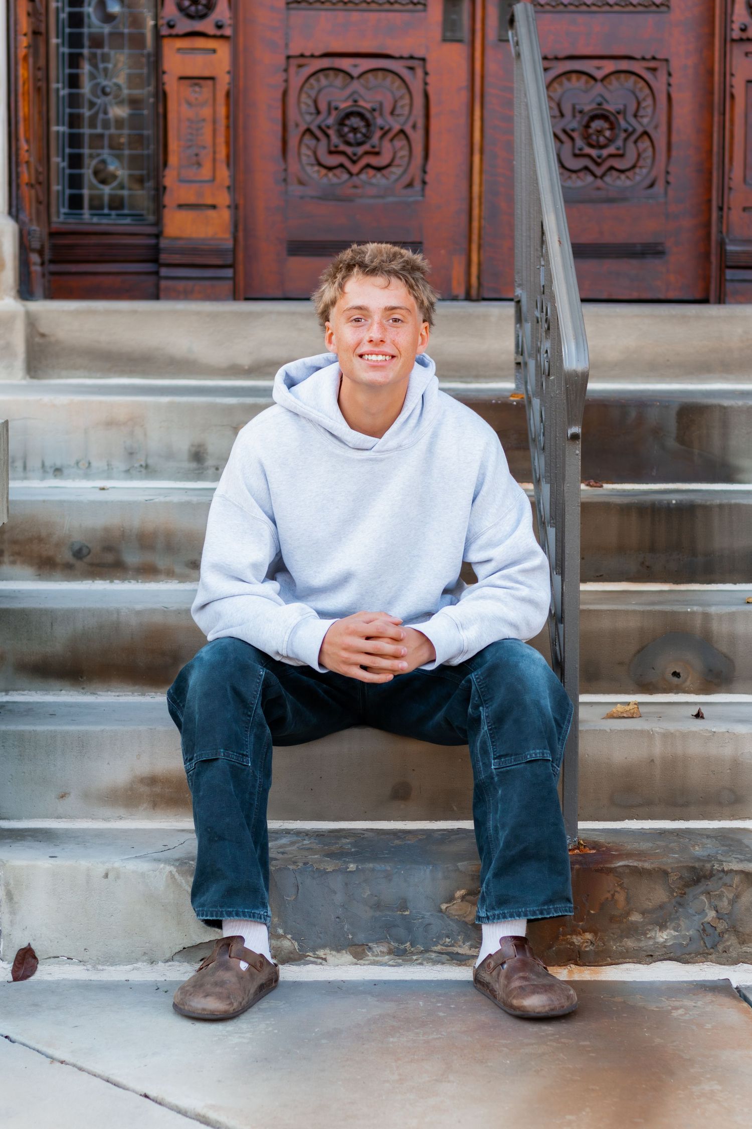 Senior sitting on steps smiling at camera.