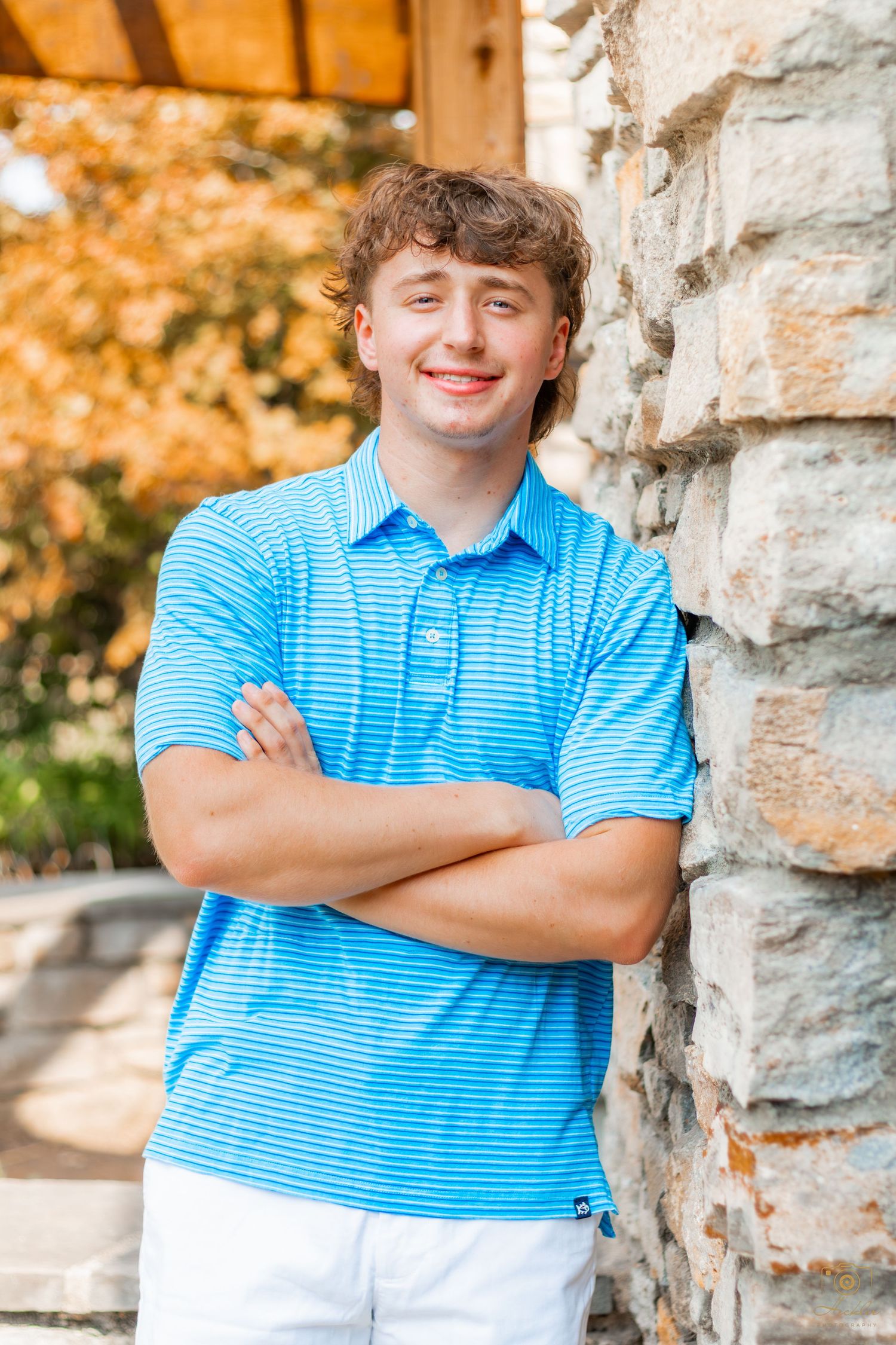 Senior leaned up wall smiling at camera.
