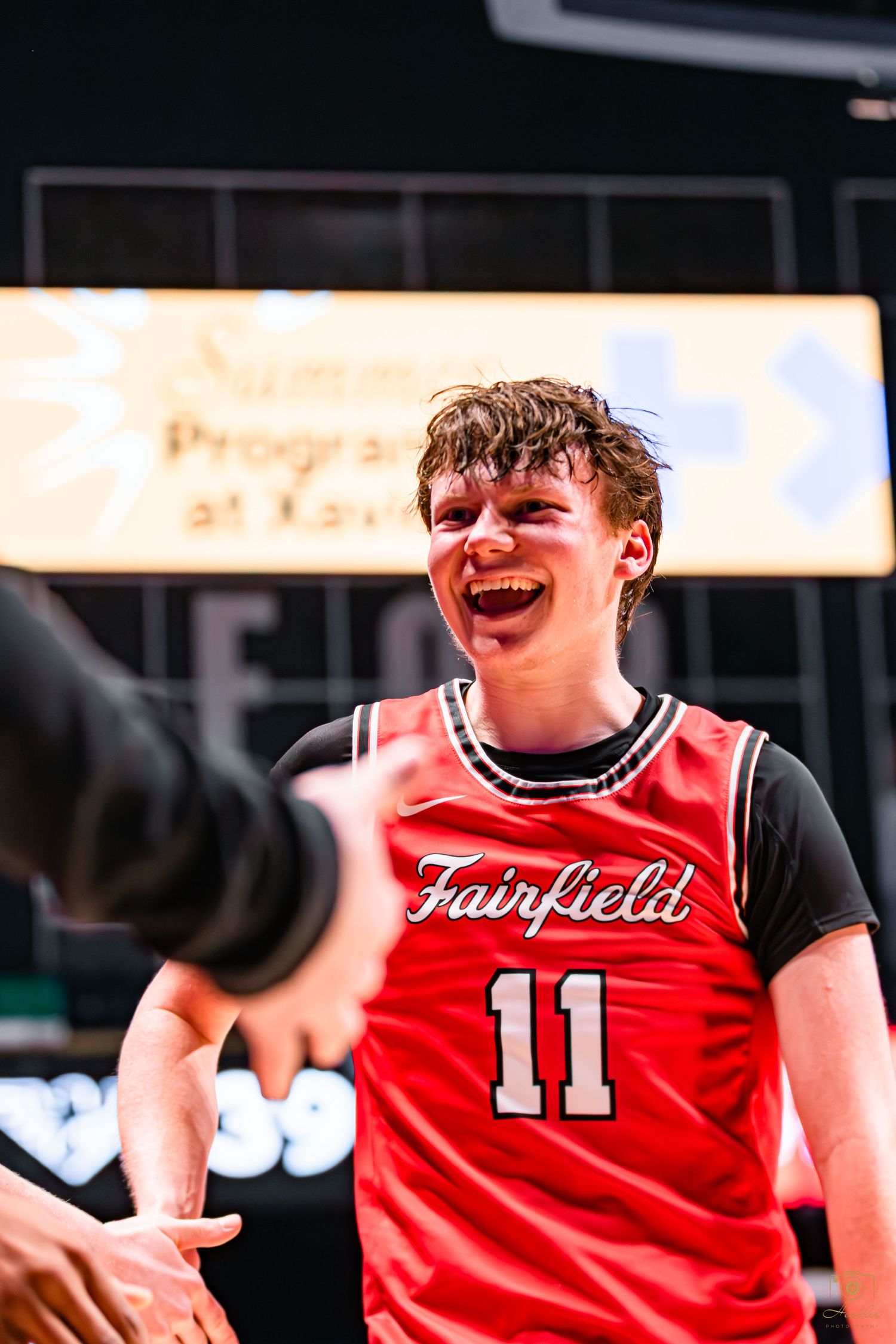 Basketball player walking down the team line smiling.