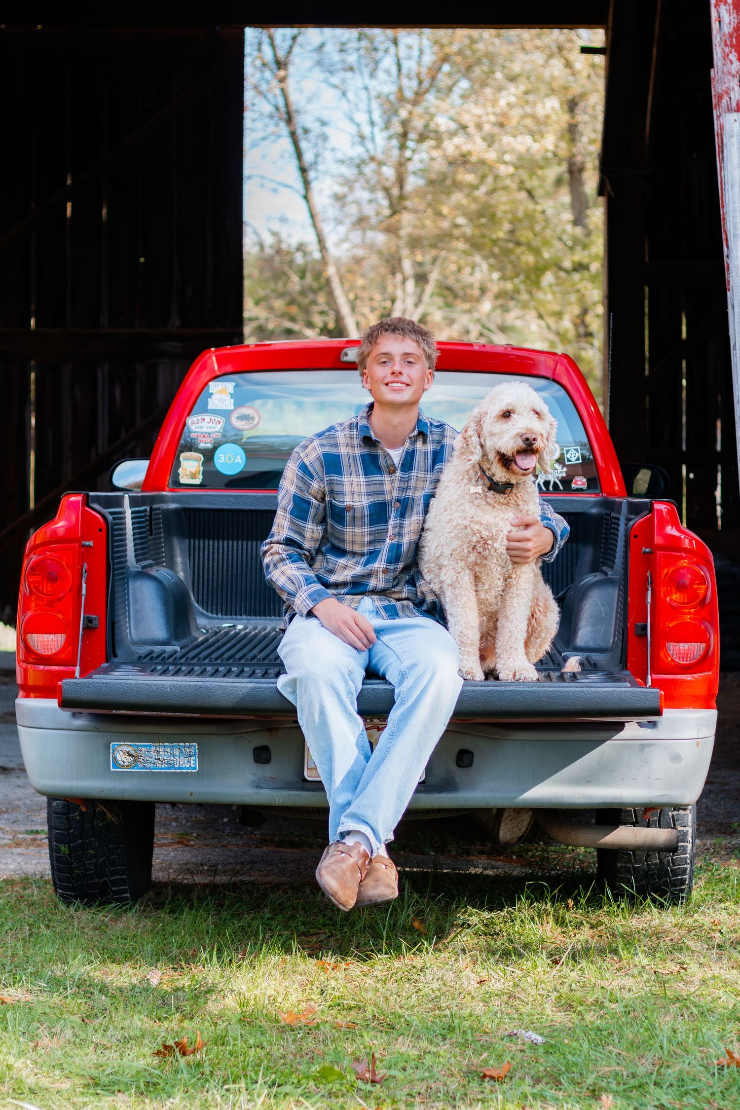 Senior smiling sitting on the back on the truck with his dog smiling at the camera.