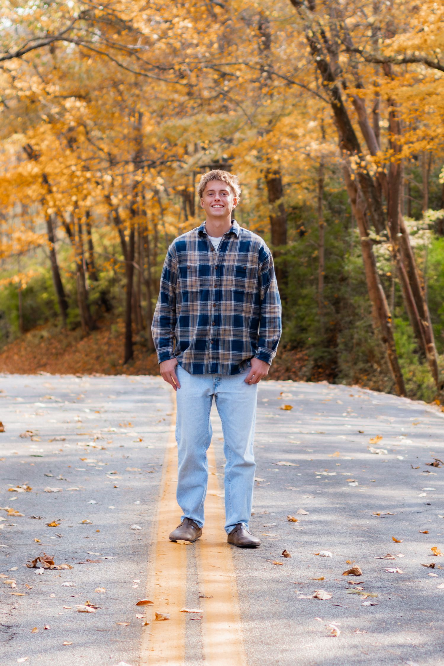 Senior standing in the middle of the street smiling at the camera.