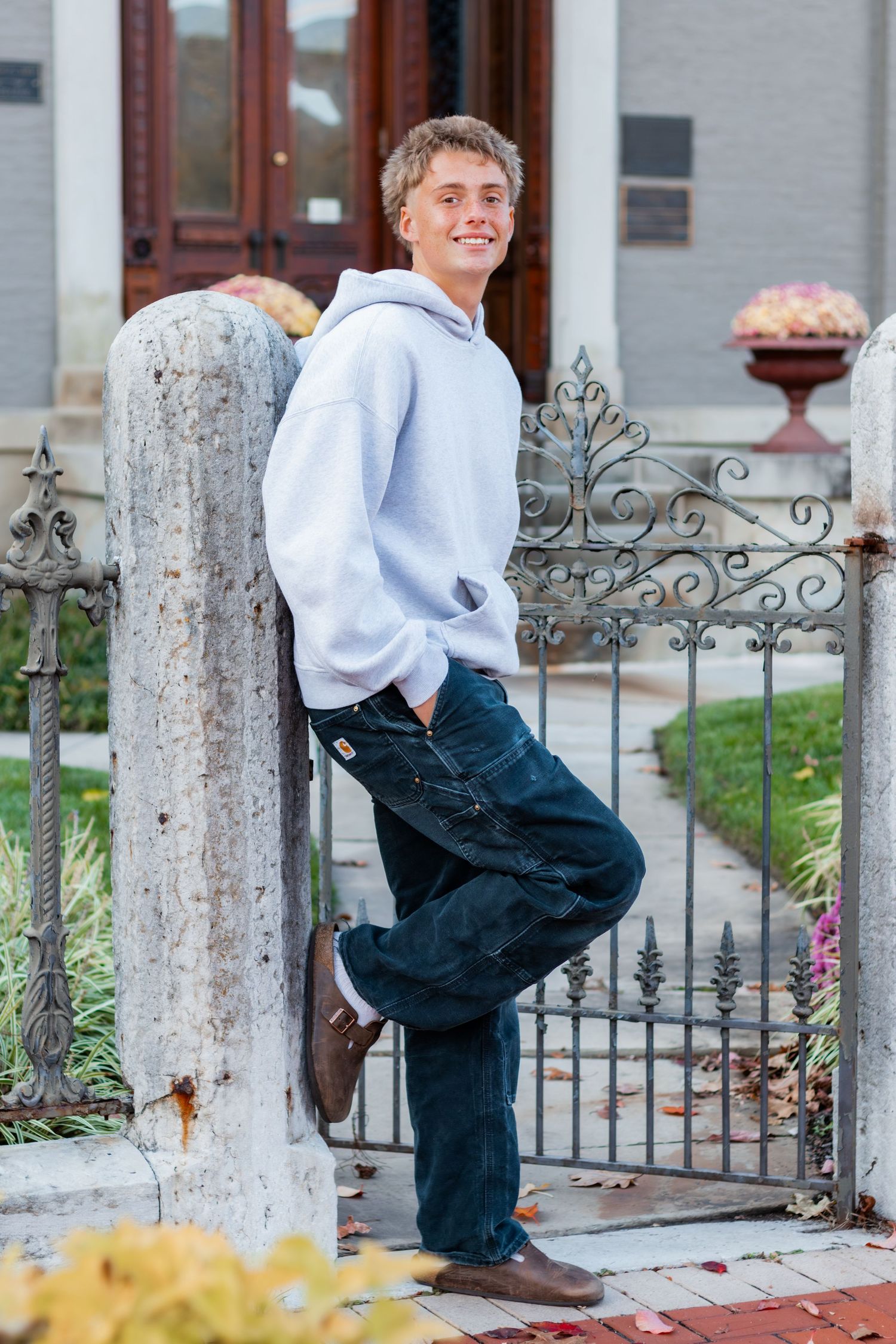 Senior up against a wall smiling.