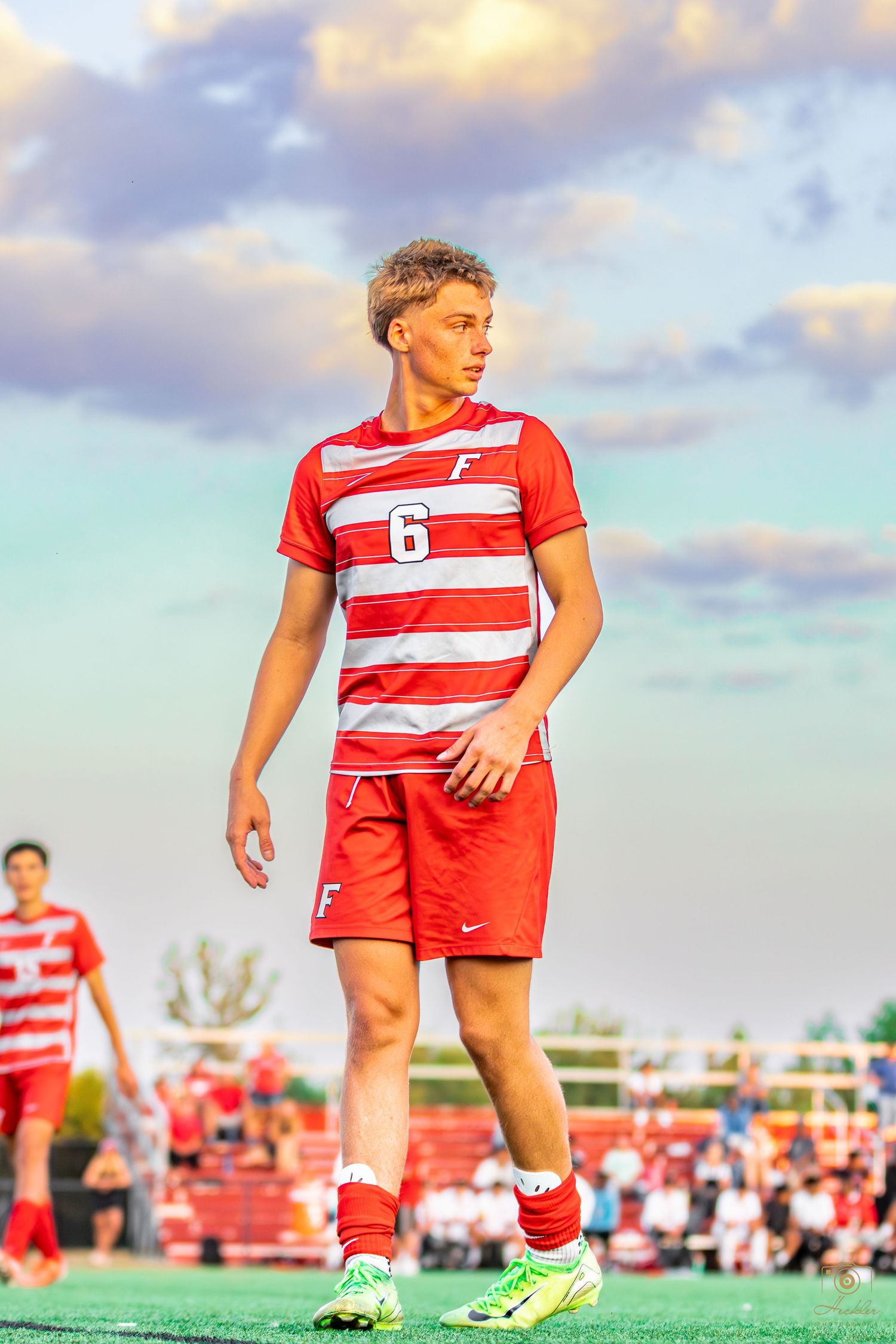 Soccer player walking towards camera with cool sunset in the background.