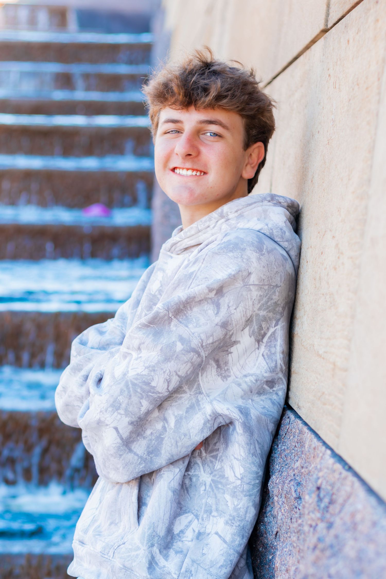 Senior up on the wall smiling.
