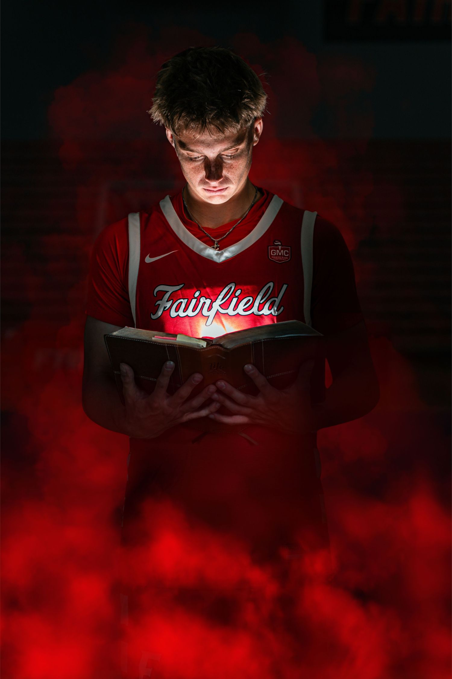 Basketball senior holding bible with light flashing in the bible with smoke in the background.