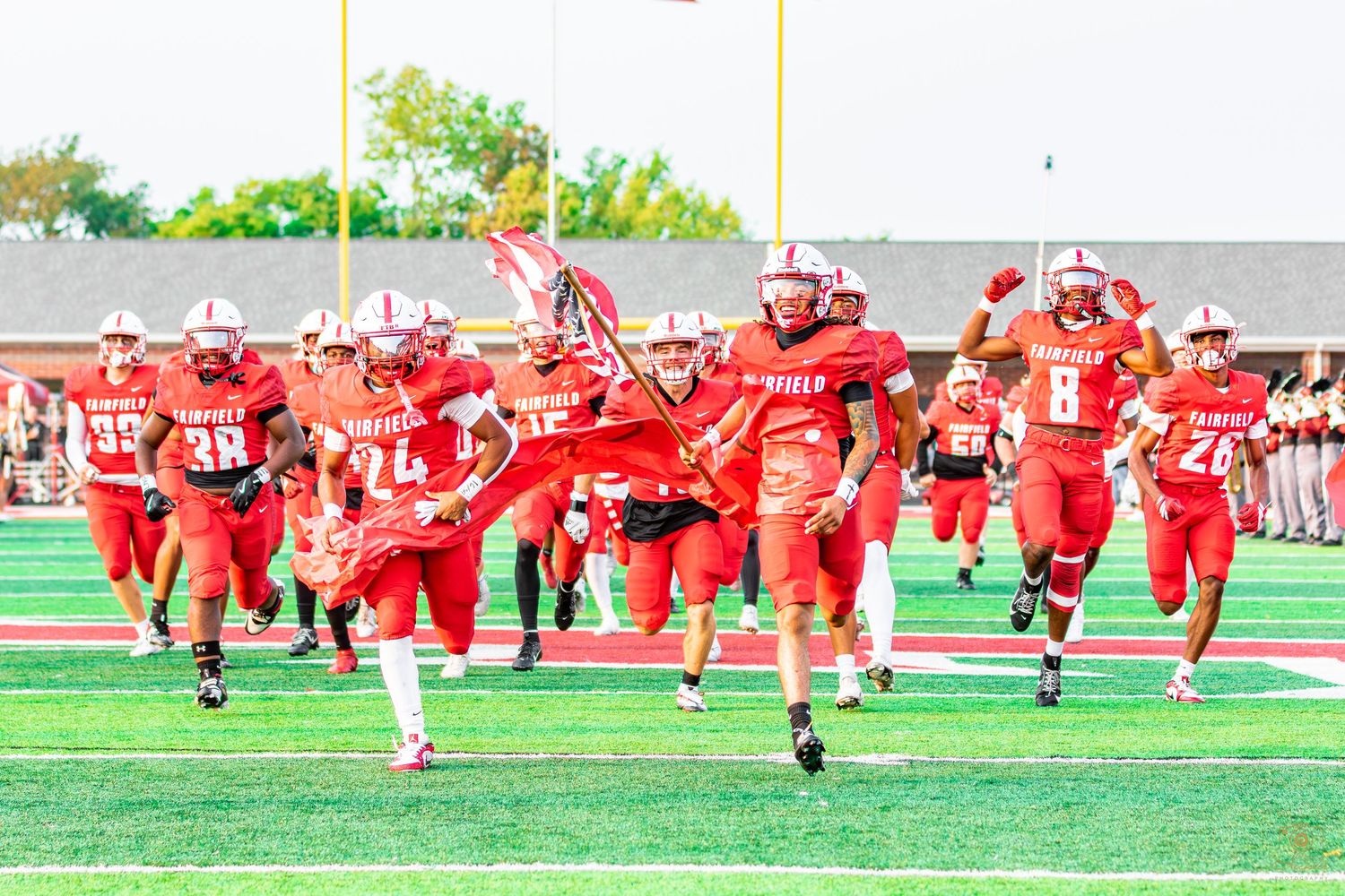 Football team running out before a game ripping a banner.
