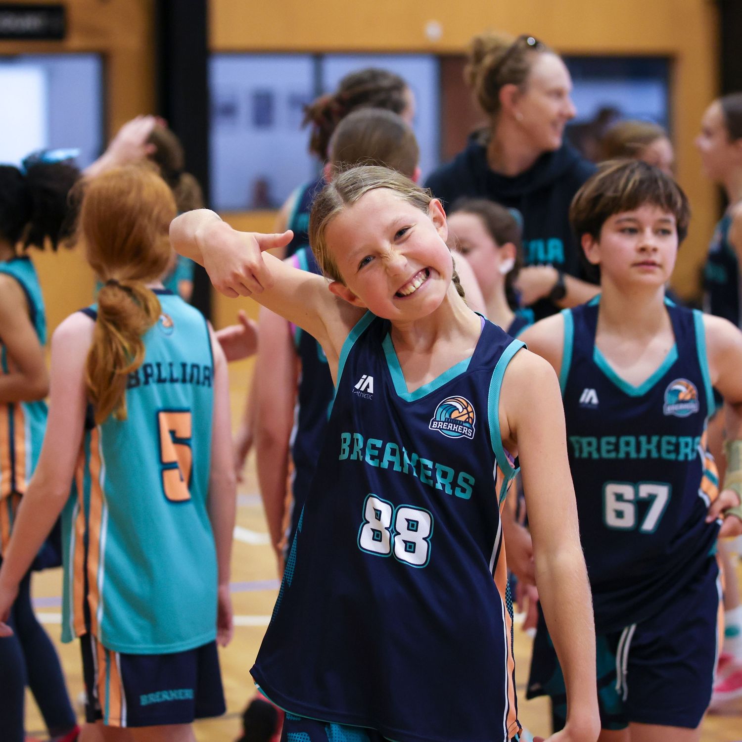 Youth basketball players in teal and navy uniforms line up during a game.