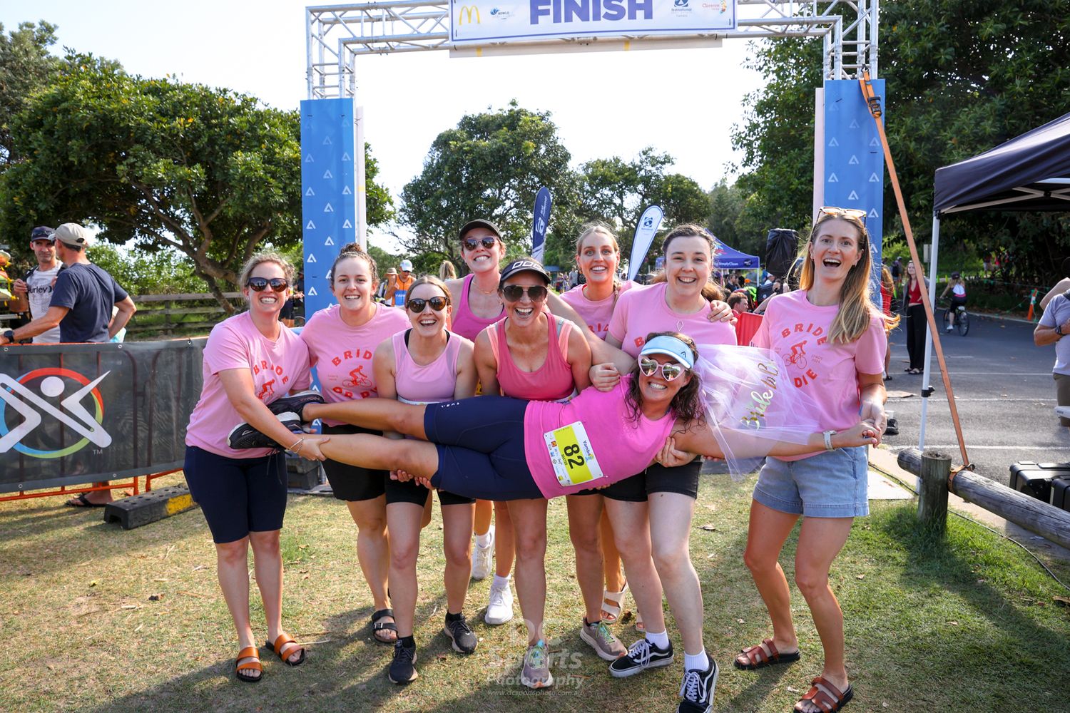 Participants gather at a race finish line banner during an outdoor running event.