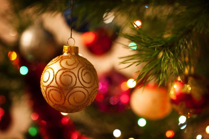 Close-up of glittering Christmas ornaments and lights on a decorated evergreen tree.