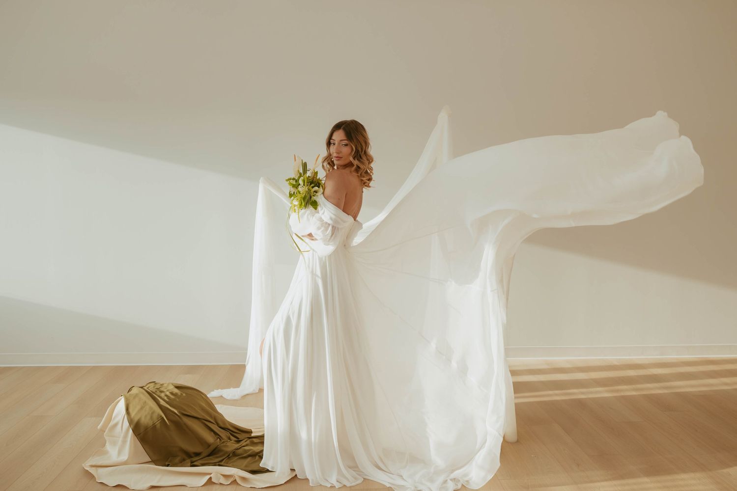 Bride in flowing white wedding dress with veil spinning gracefully in natural light.
