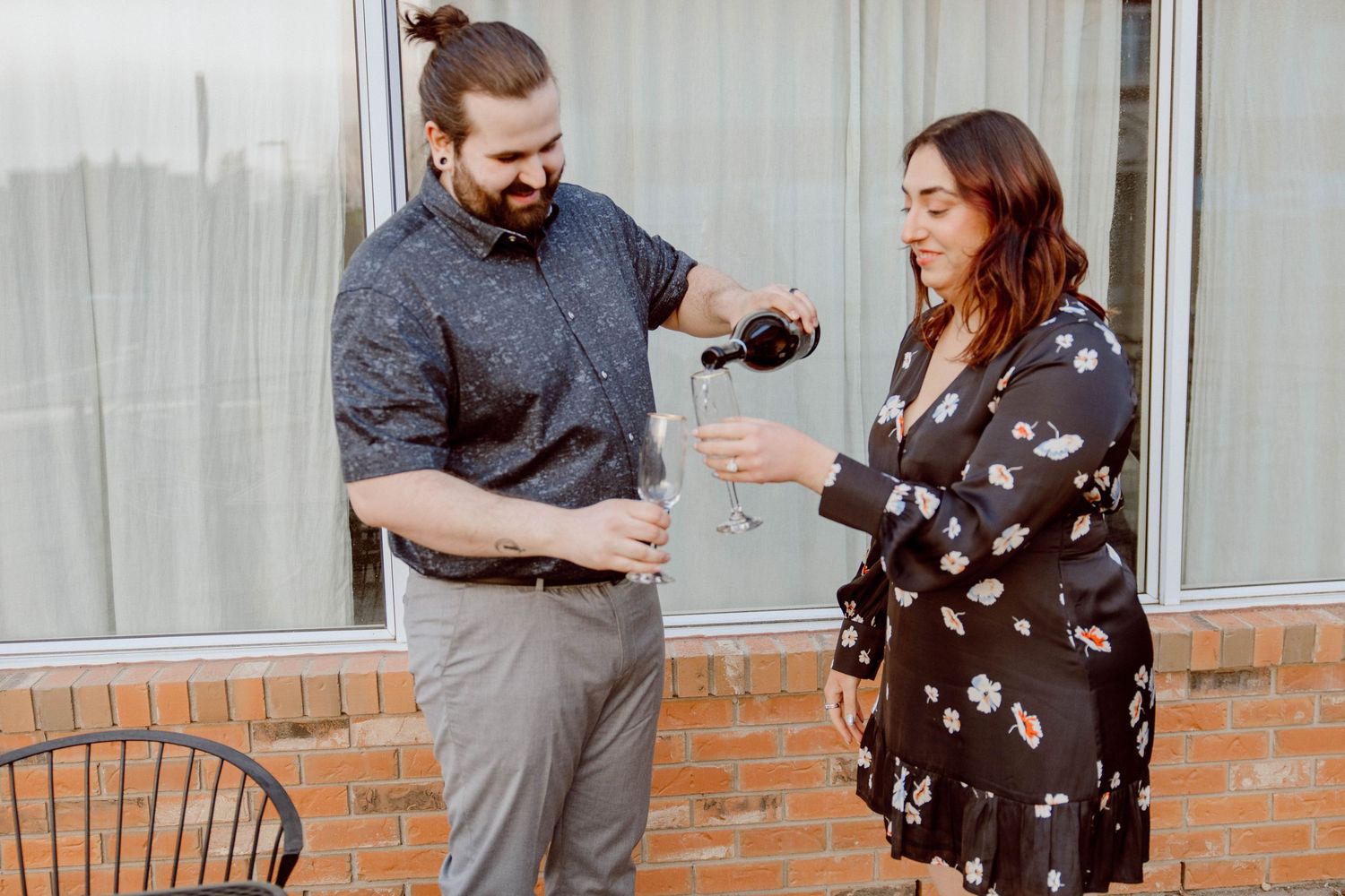 Couple sharing a celebratory toast with champagne glasses on an outdoor patio.
