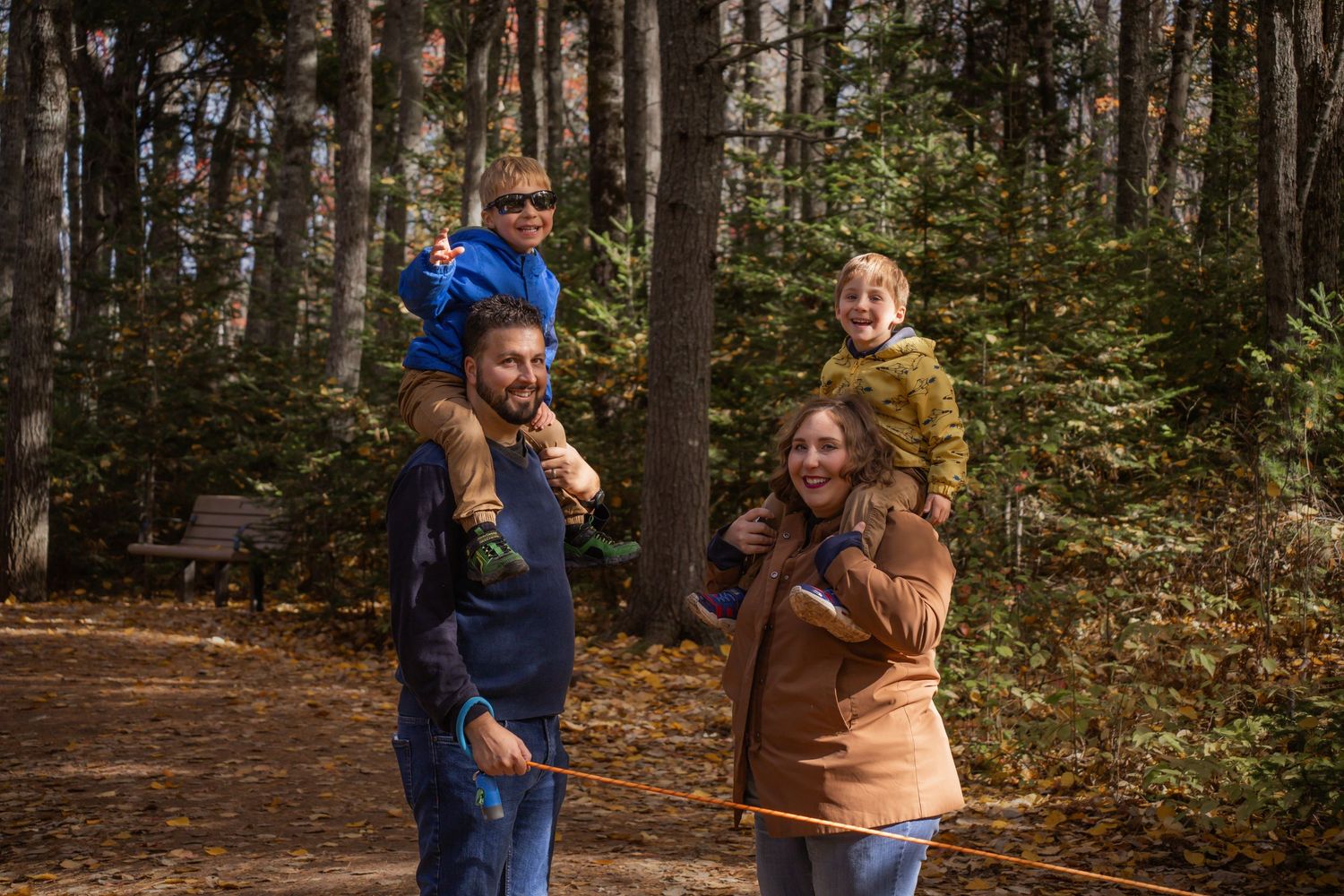 A group of people walk together through a wooded area on an autumn day.