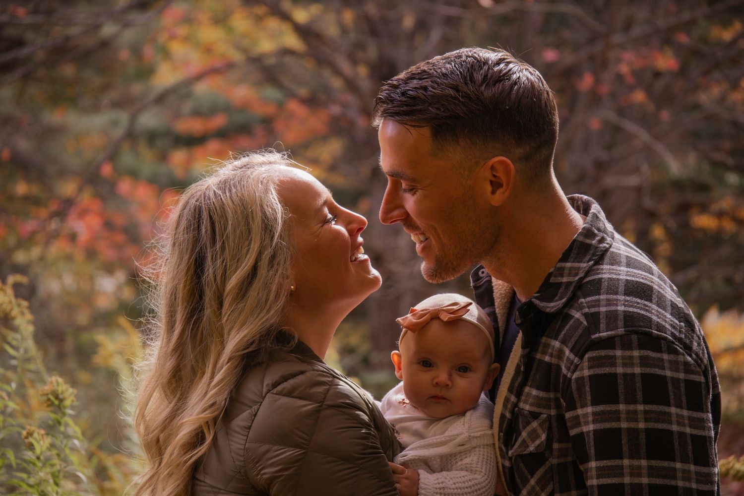 A couple shares tender moments in a fall forest setting with warm autumn colors and natural lighting.