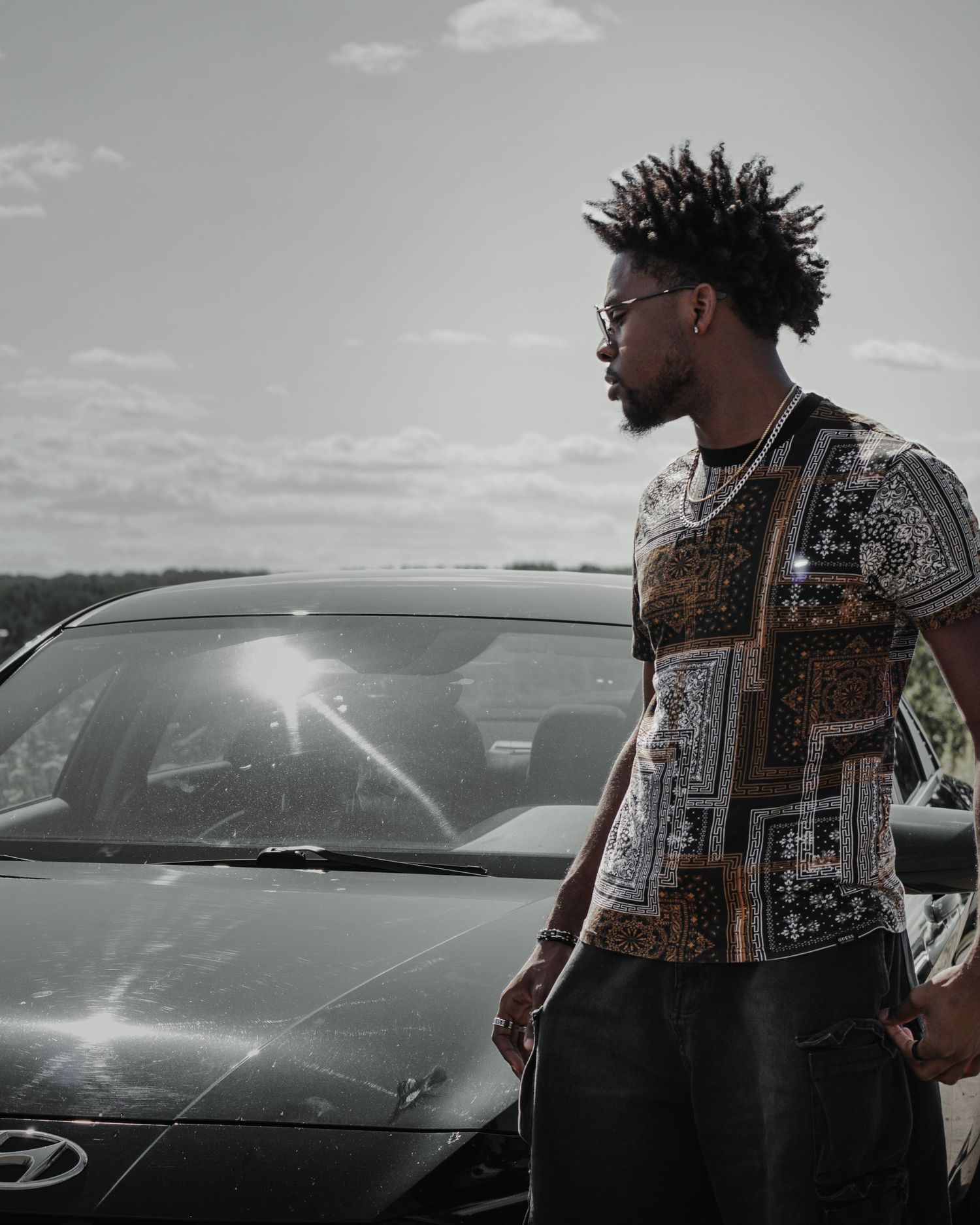 Stylish portrait showing fashionable patterned vest against car in desaturated tones.