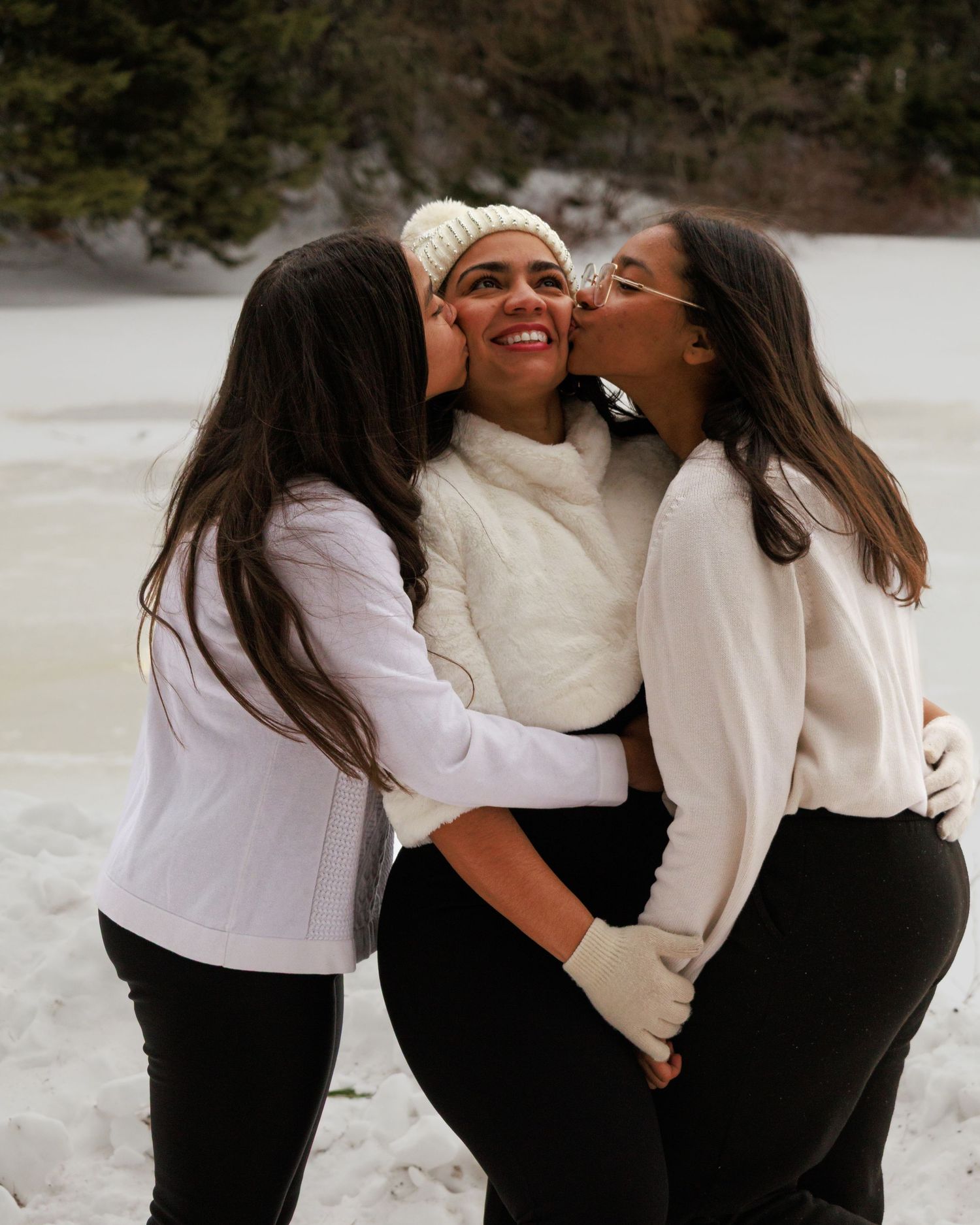 Candid winter photo showing three friends sharing an affectionate moment in the snow.