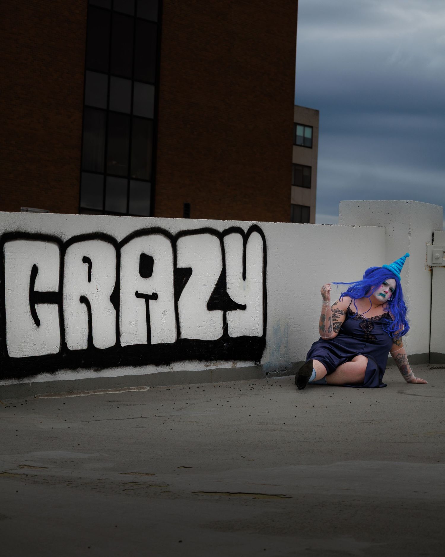 A dramatic photo series showing someone with blue hair posing against an urban wall with graffiti.