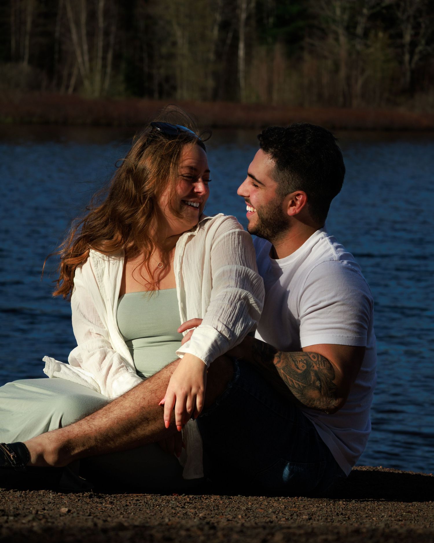 Romantic couple sharing intimate moments by a lakeside at sunset.