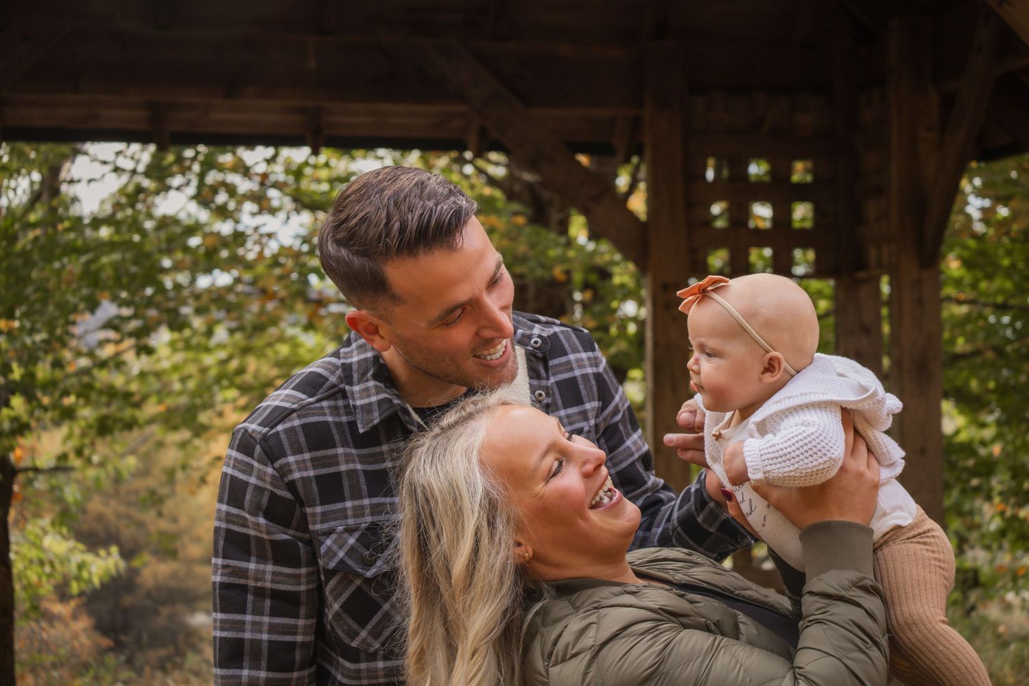 A series of candid outdoor family photos showing tender moments between parents and baby in a natural setting.
