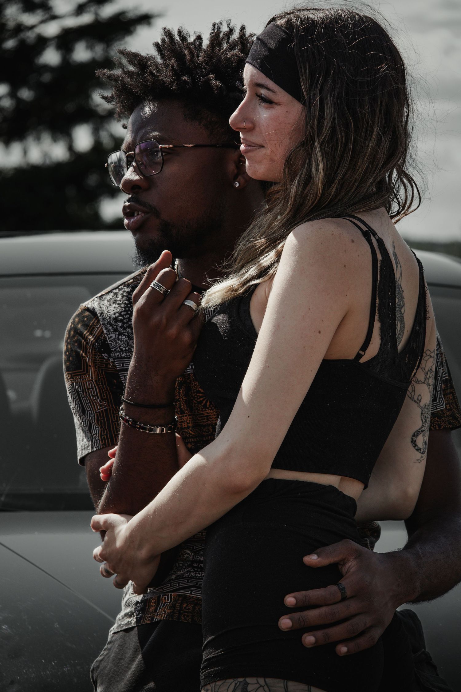 Couple in intimate embrace against dark moody background with urban setting.