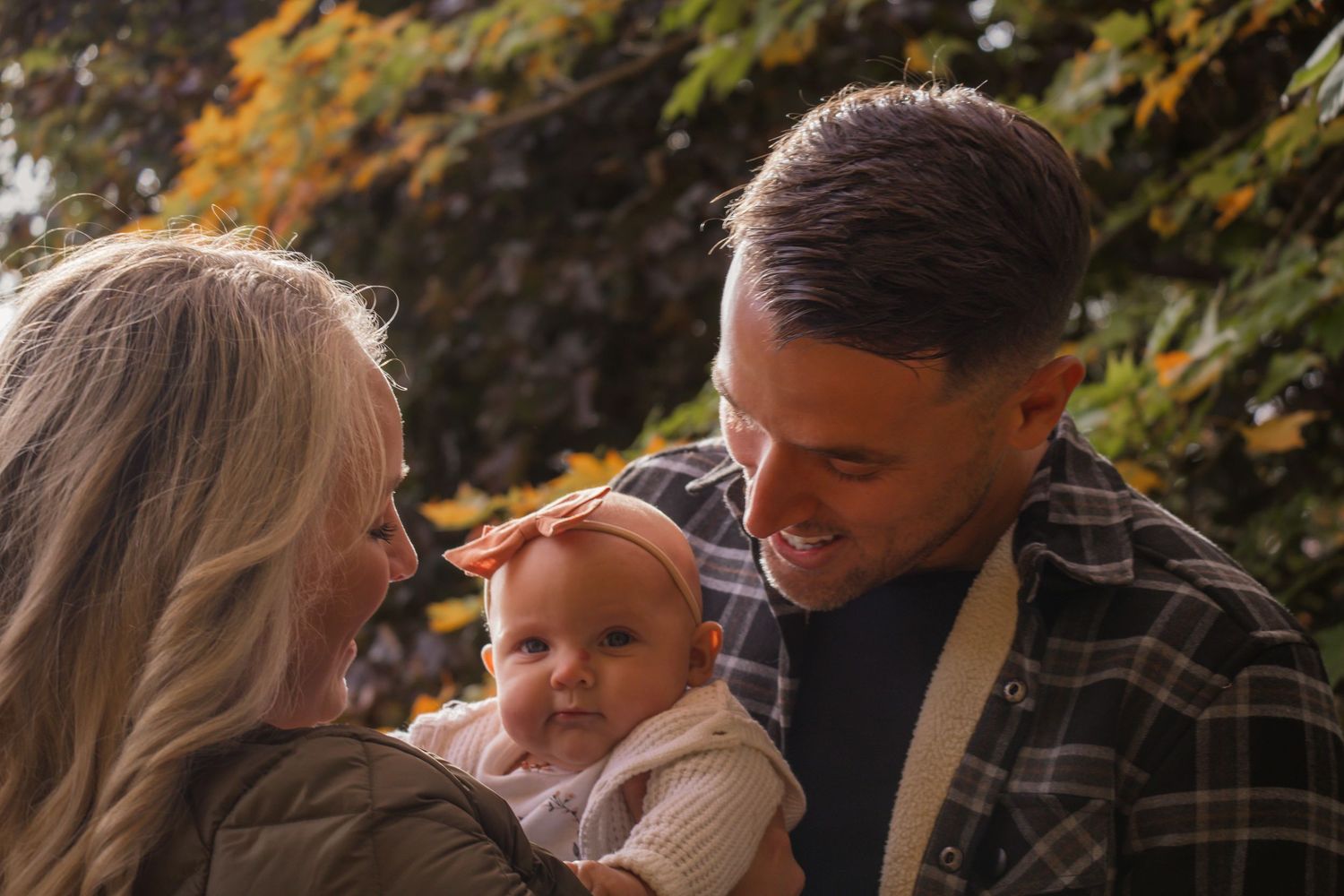 Family enjoying a warm autumn day outdoors together while sharing snacks and laughing.