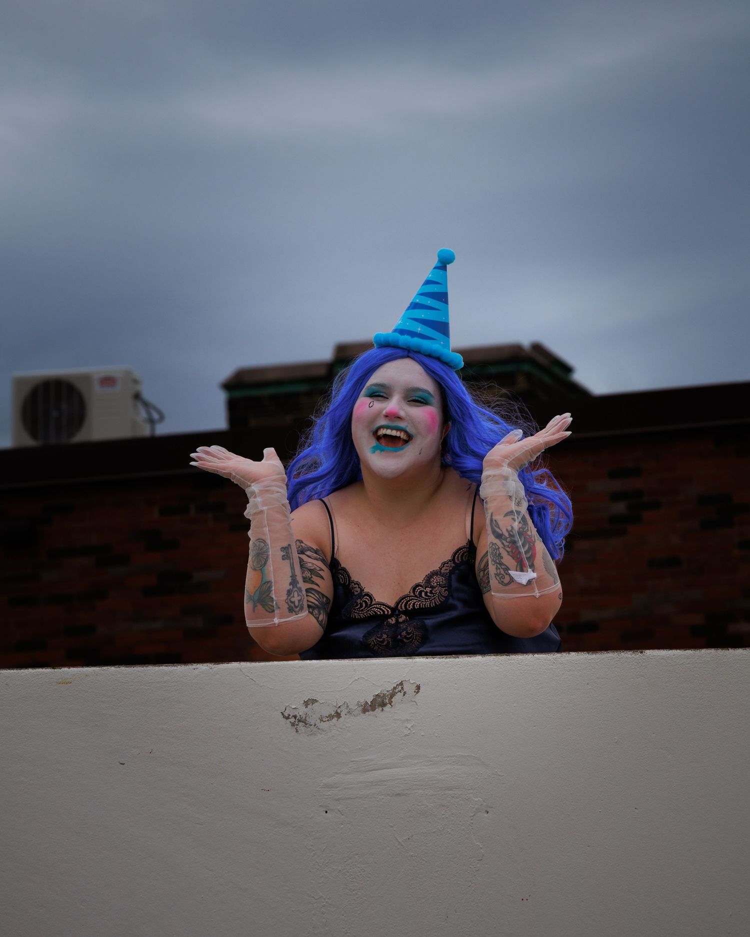 A sequence showing someone with blue hair and theatrical makeup expressing joy over a wall.