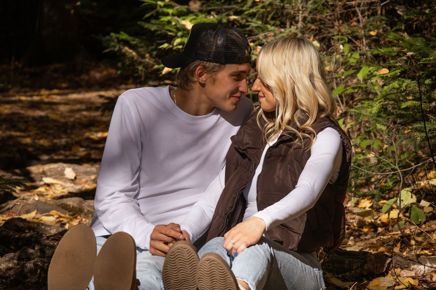A romantic couple embraces on a wooded path during an autumn engagement photo session.
