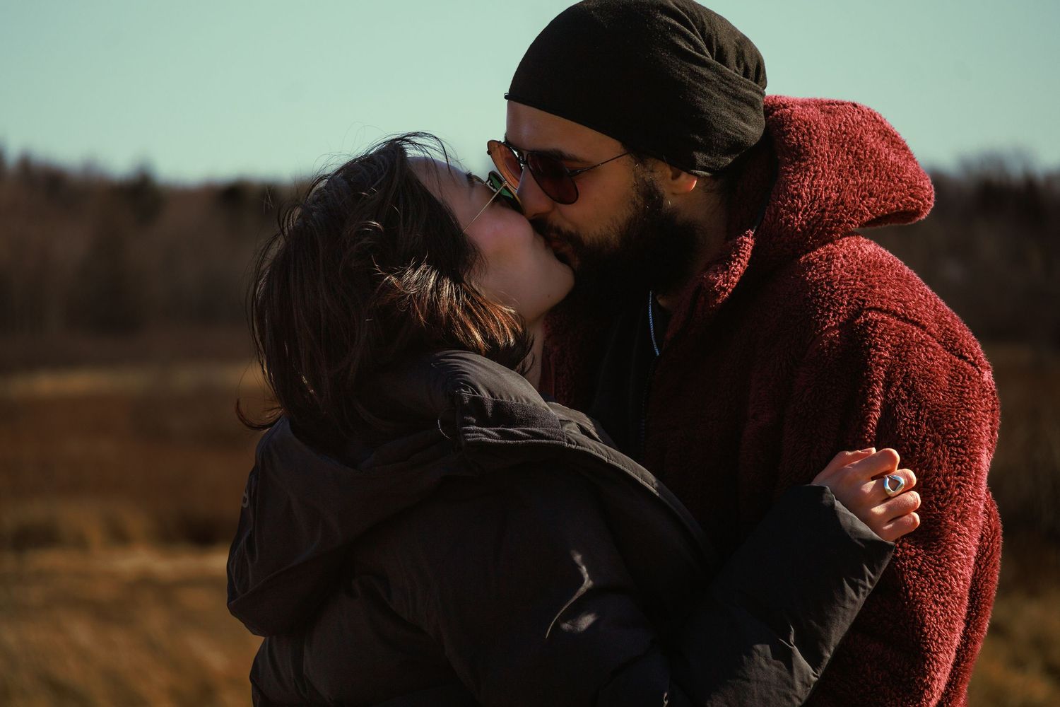 Intimate moment between couple wearing cozy winter sweaters at sunset.