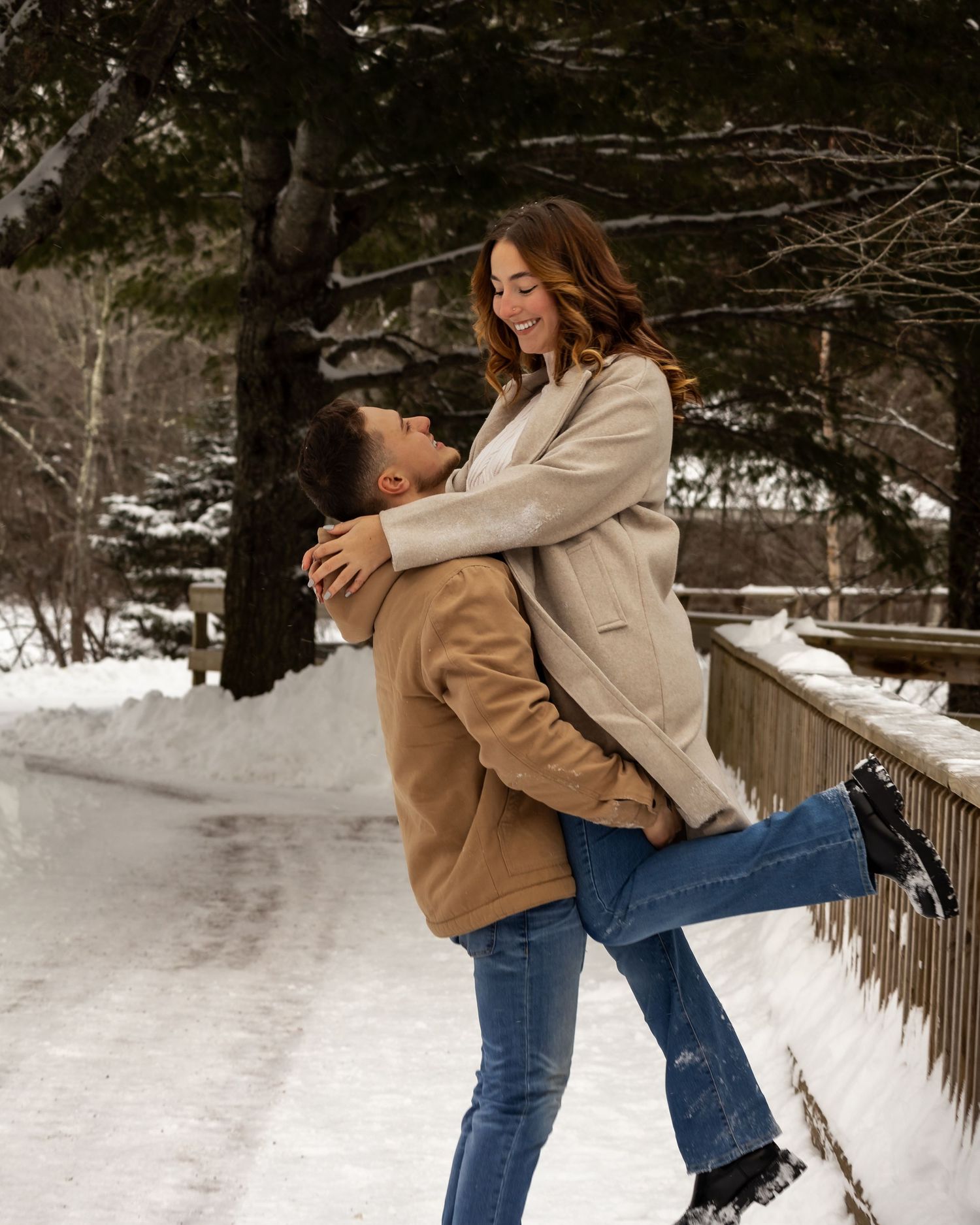 Dancing couple celebrates joyfully in a snow-covered winter landscape.