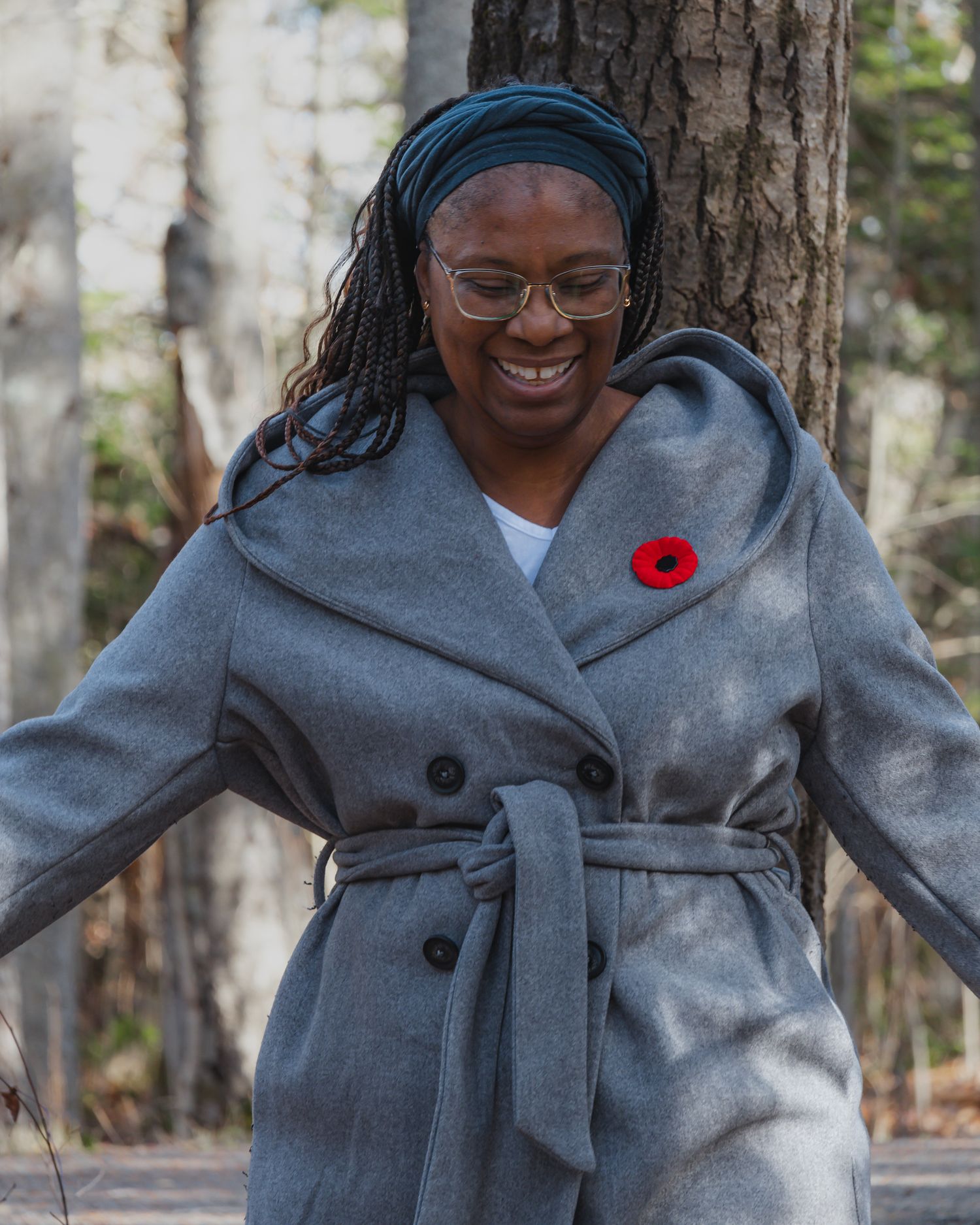 Person wearing a cozy gray winter coat with large buttons poses against snowy forest backdrop.