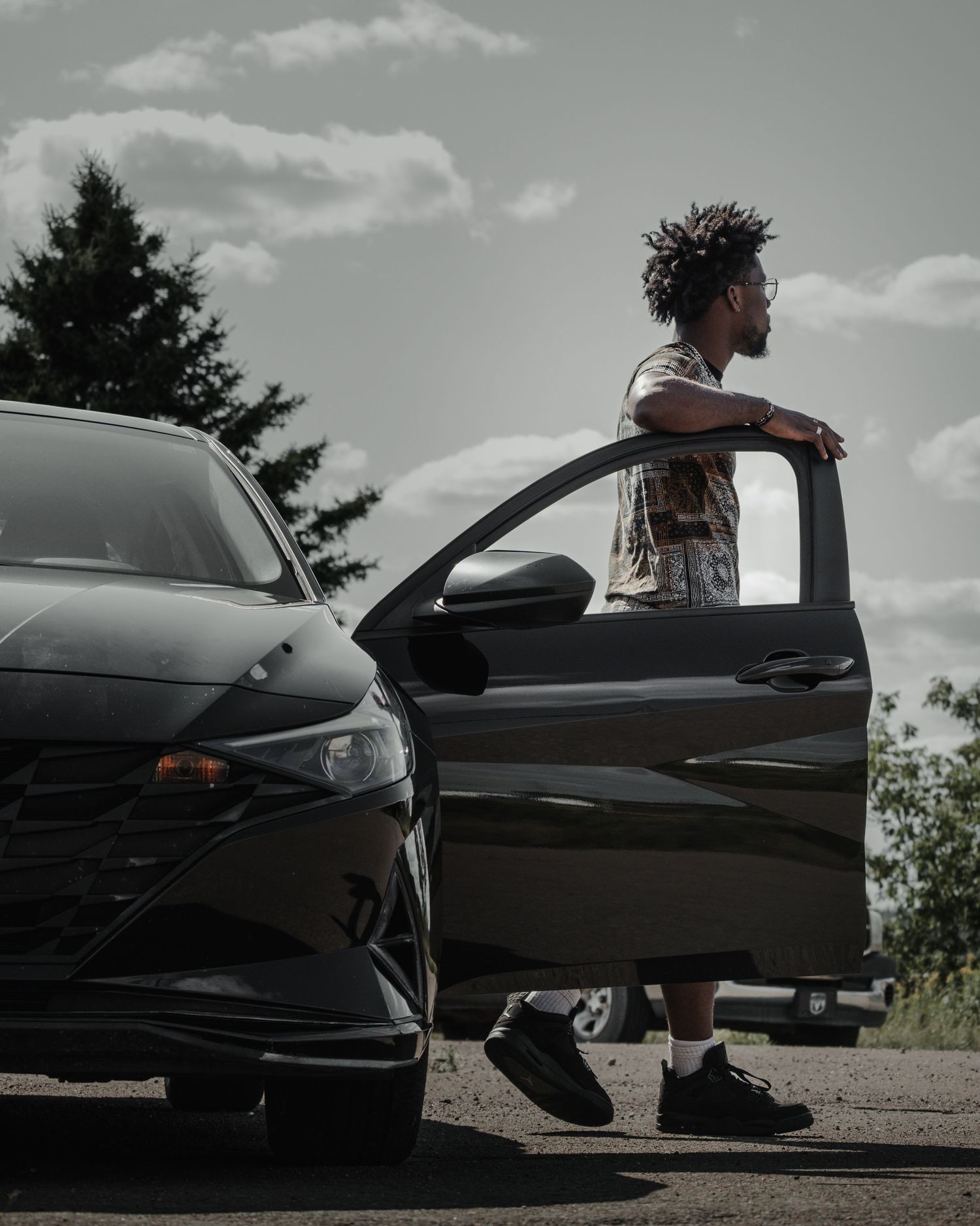 A sequence of black and white photos showing someone resting their arm on a black car's hood.