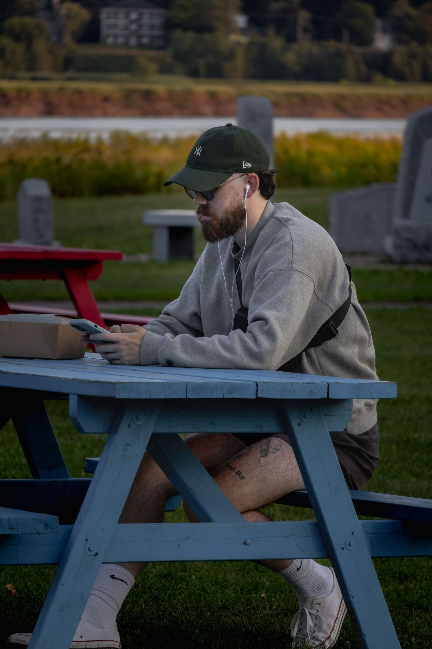 Person relaxing on a blue picnic table in casual attire during golden hour.