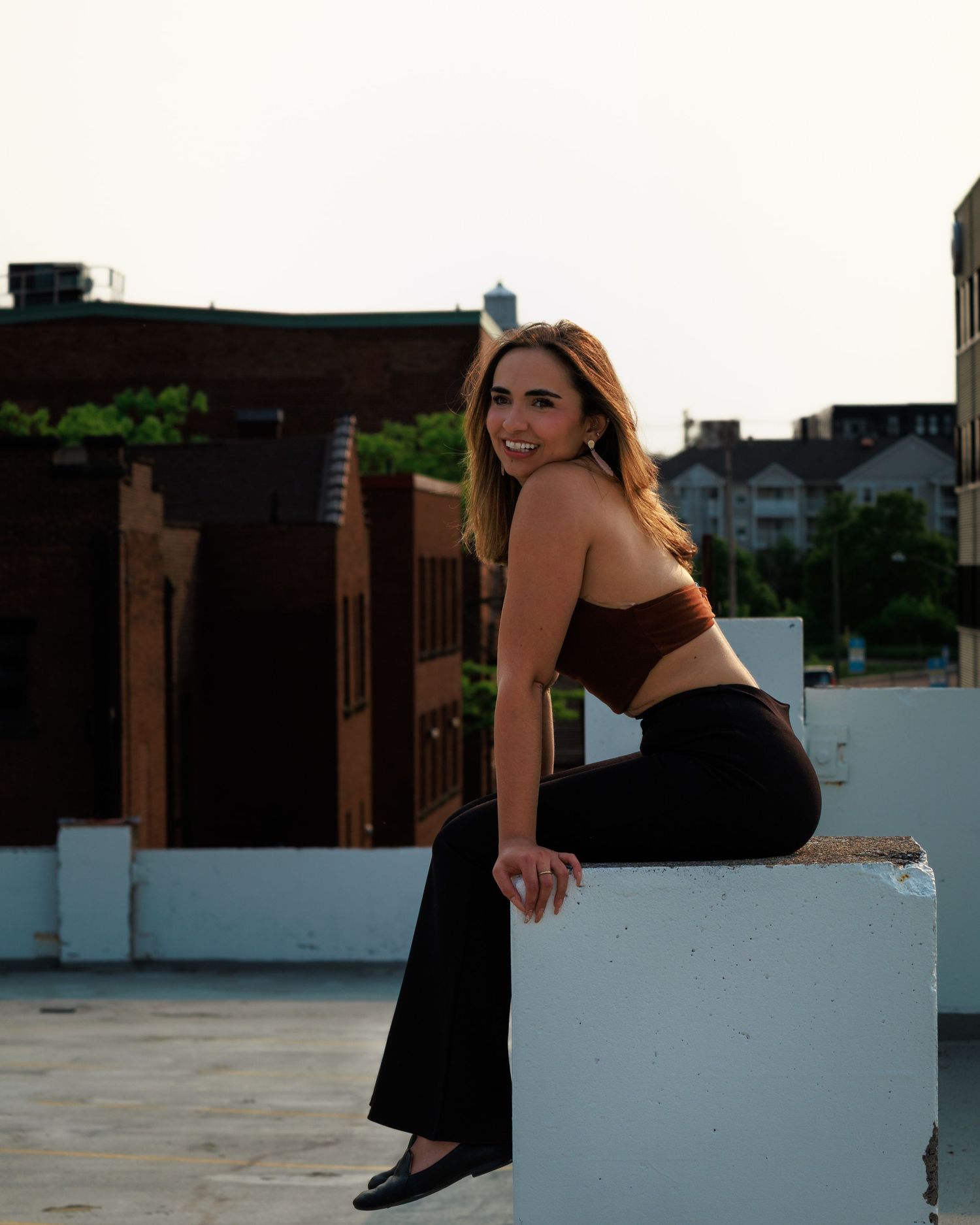 Stylish athletic wear photo showing dark activewear outfit against urban rooftop setting at sunset.