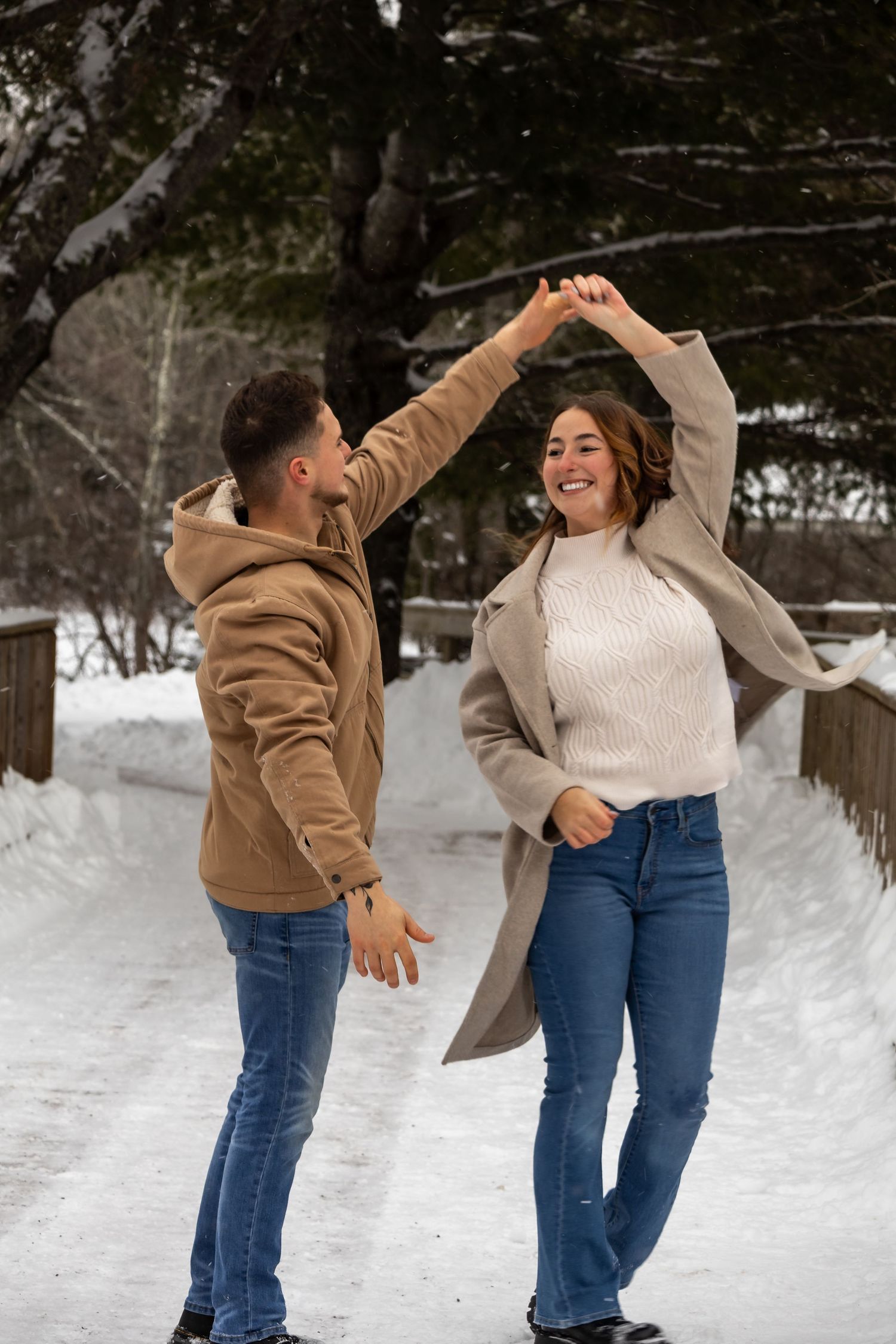 Playful dance sequence of couple in winter clothing against snowy backdrop.