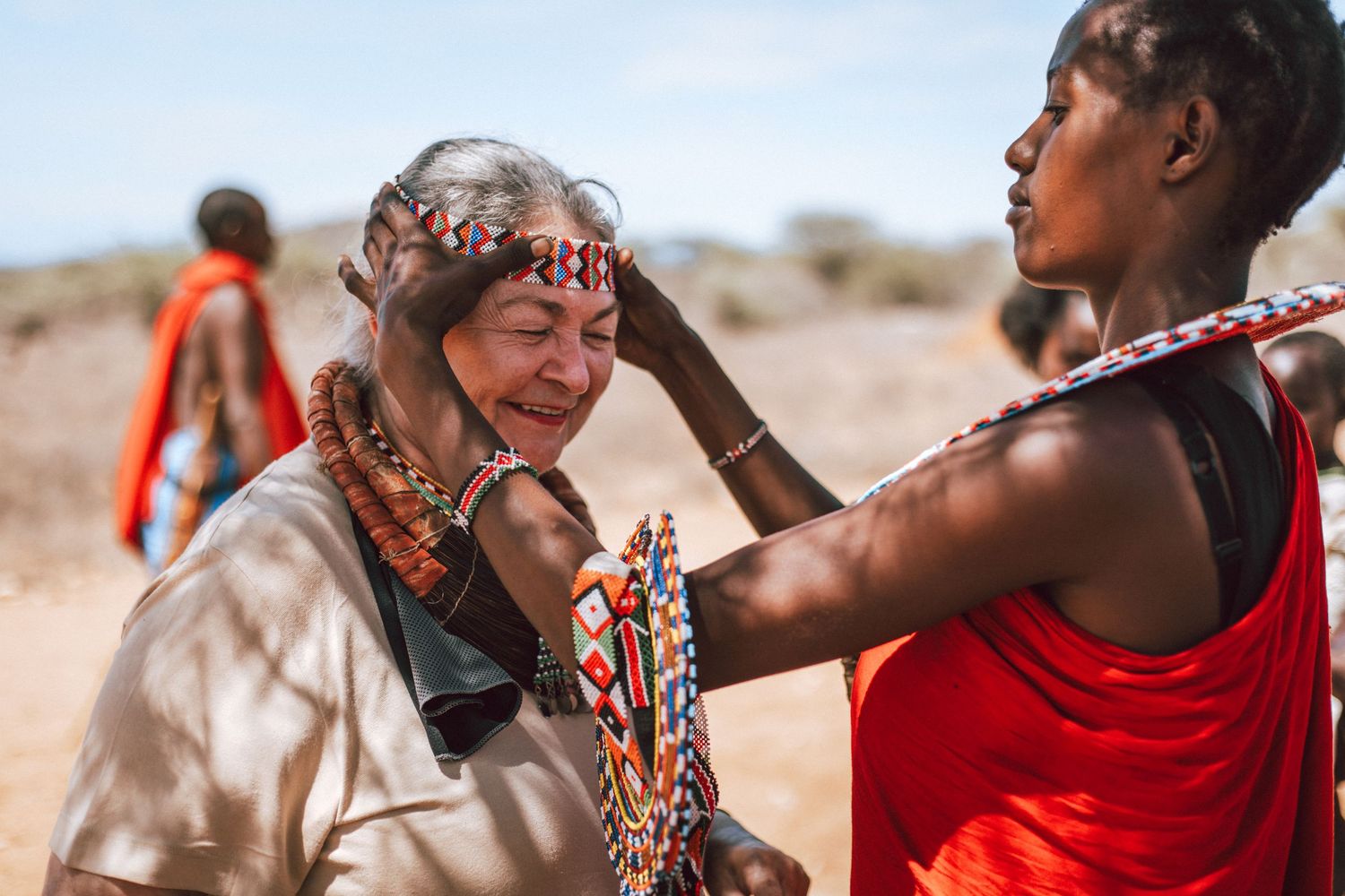 Samburu cultural visit to a village, Samburu lady putting beaded jewellery on a visitor
