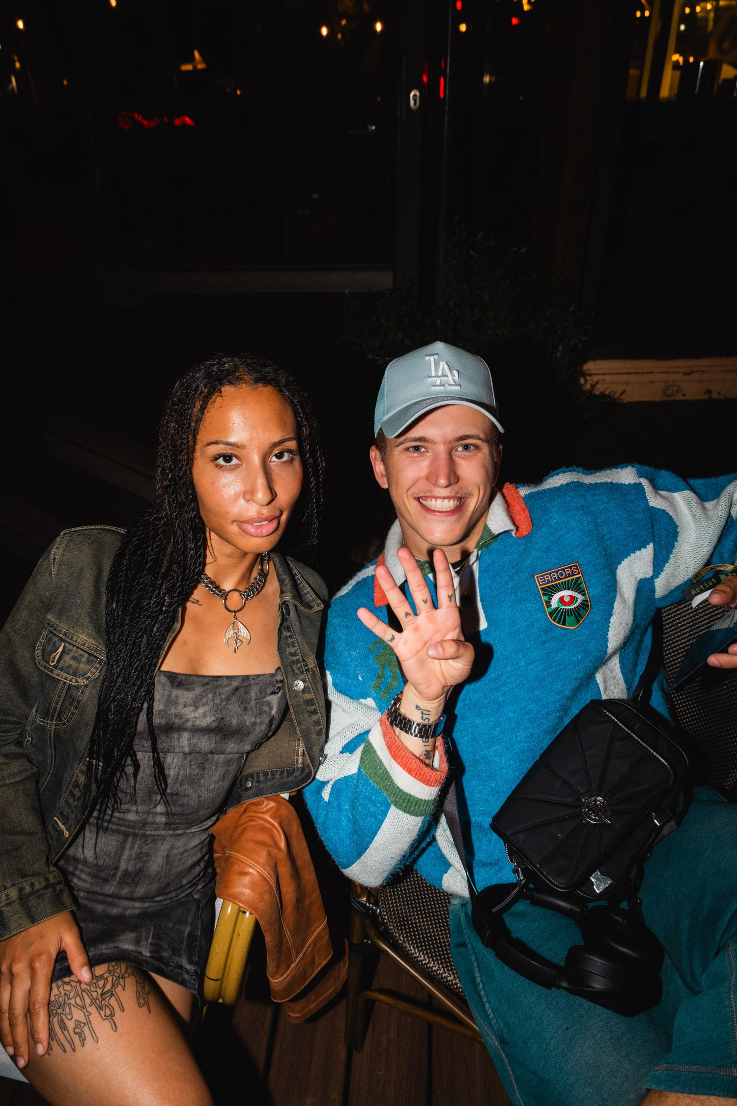 Friends relaxing on a blue couch at a casual nighttime gathering.