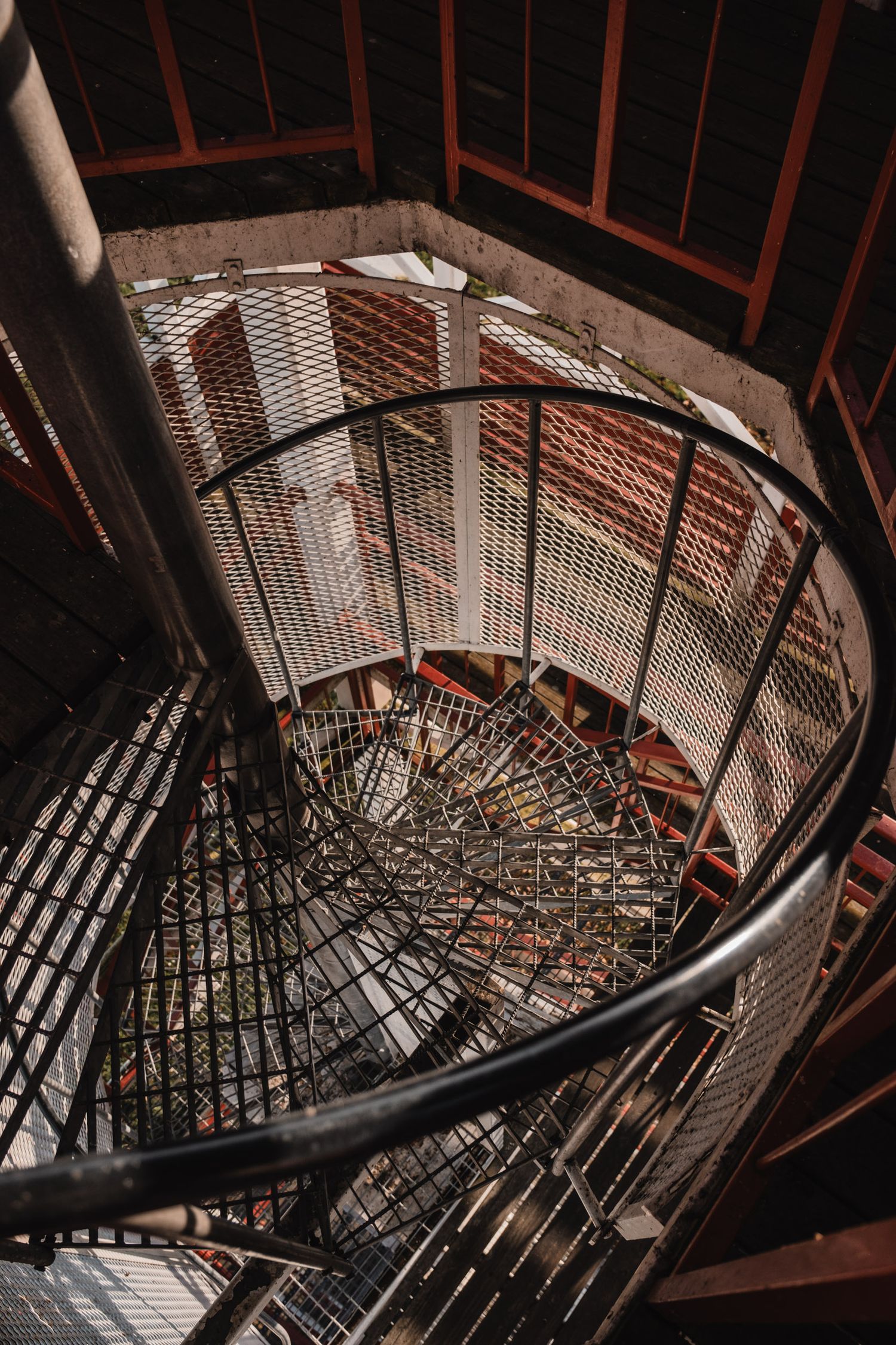 Spiral staircase with metal grating steps descending in dramatic industrial setting.