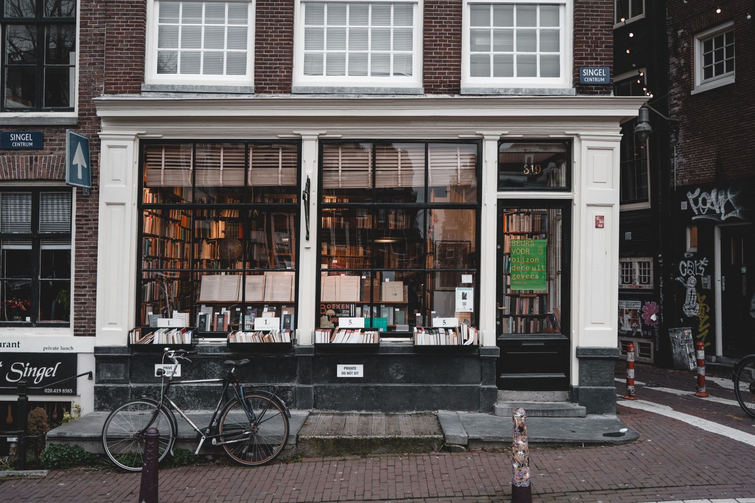 Row of brick storefronts with large windows and bikes parked along a city street.