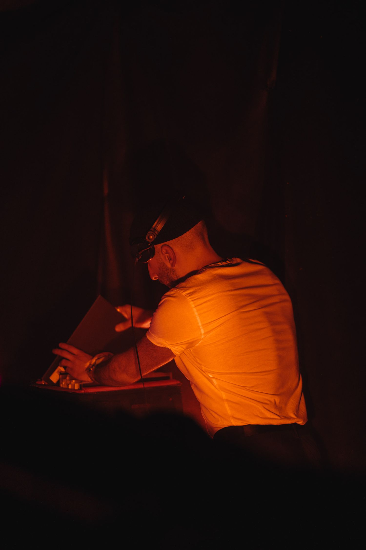 Figure in orange shirt performing in dimly lit space.